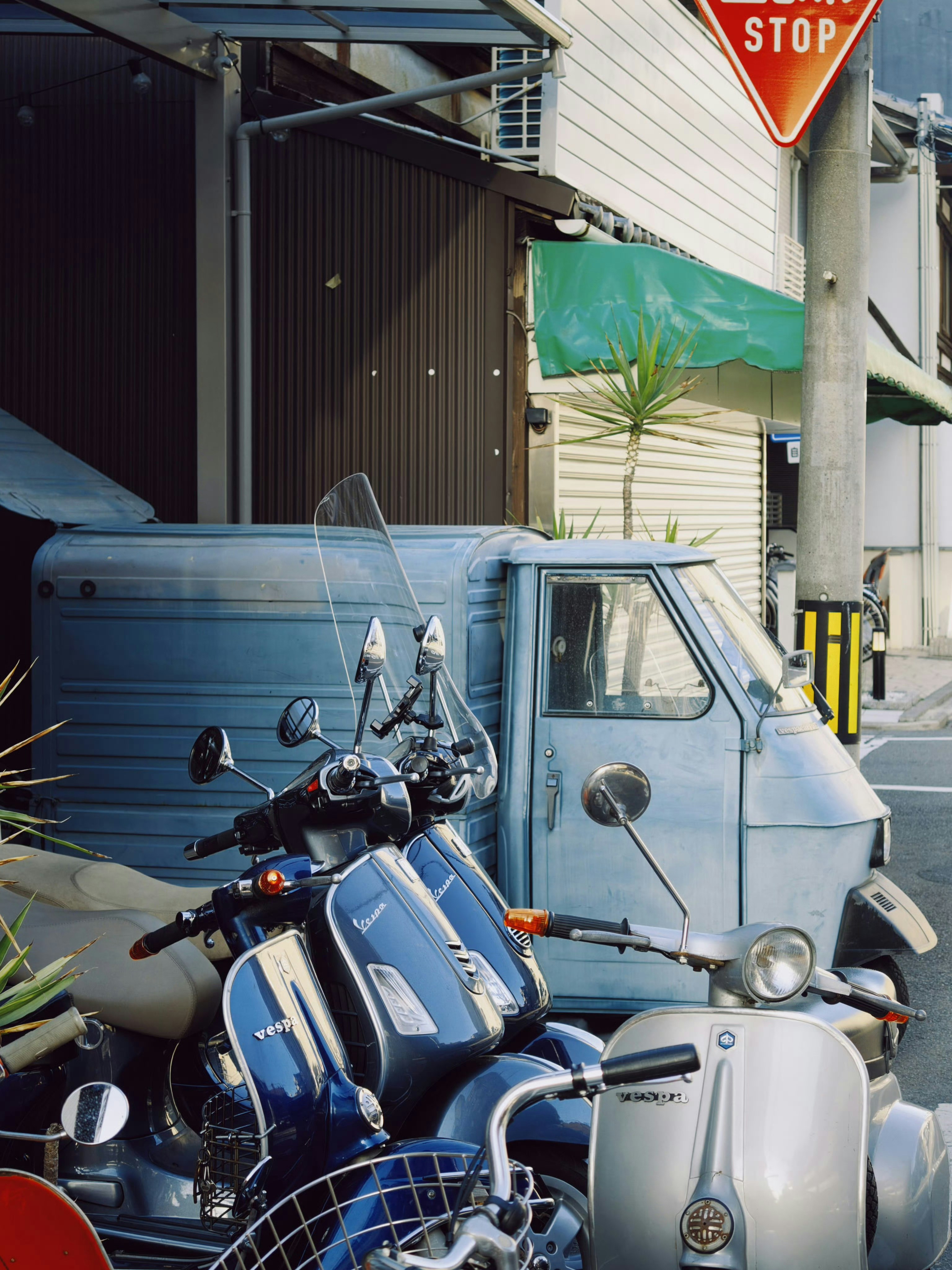 Two vespas and a three-wheeled truck parked.
