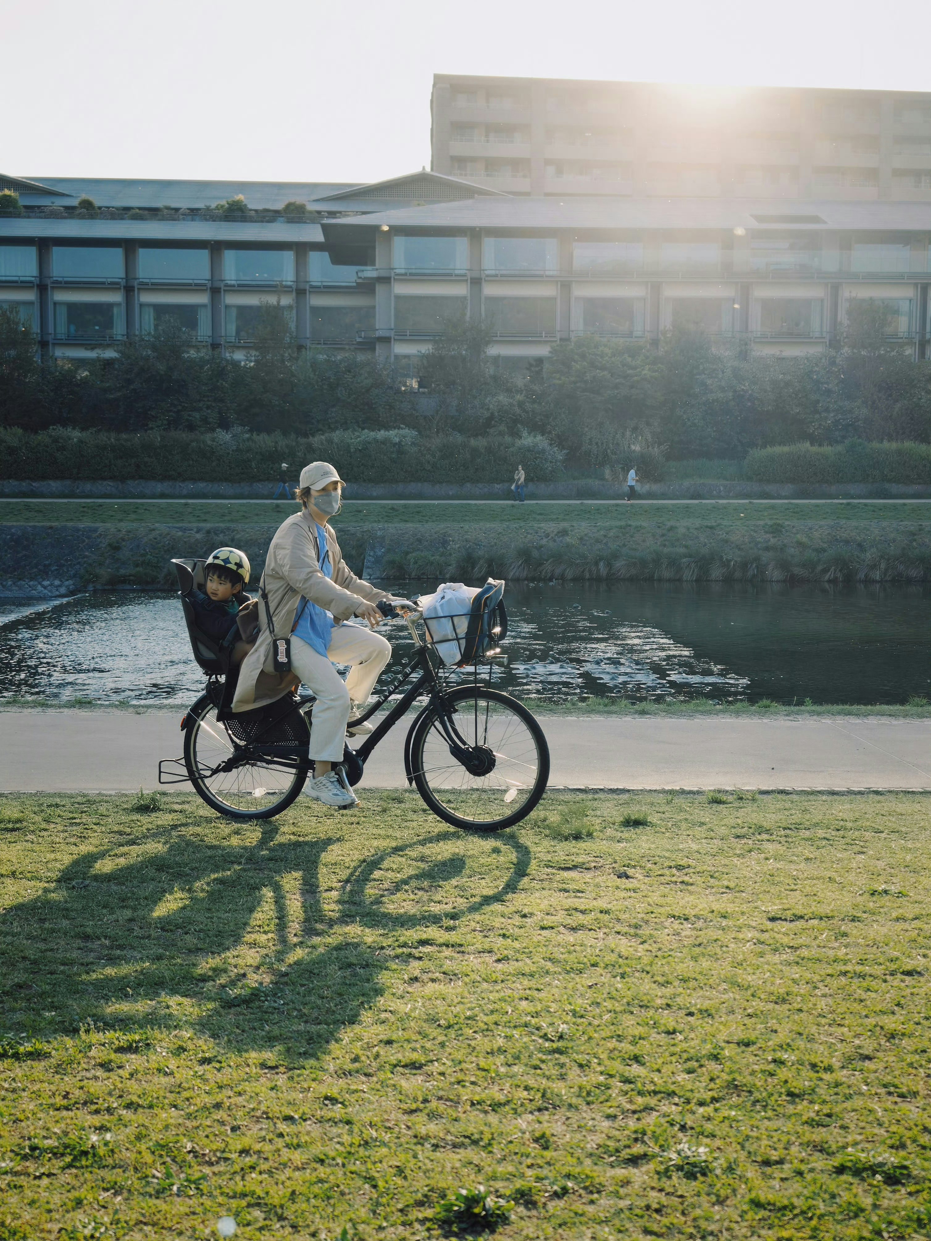 Woman rides bicycle with child in back seat.