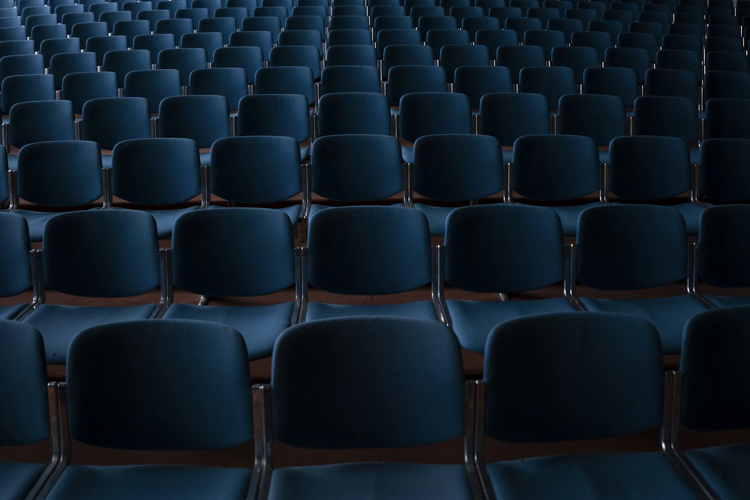 Rows of empty blue seats in a hall before the doors open