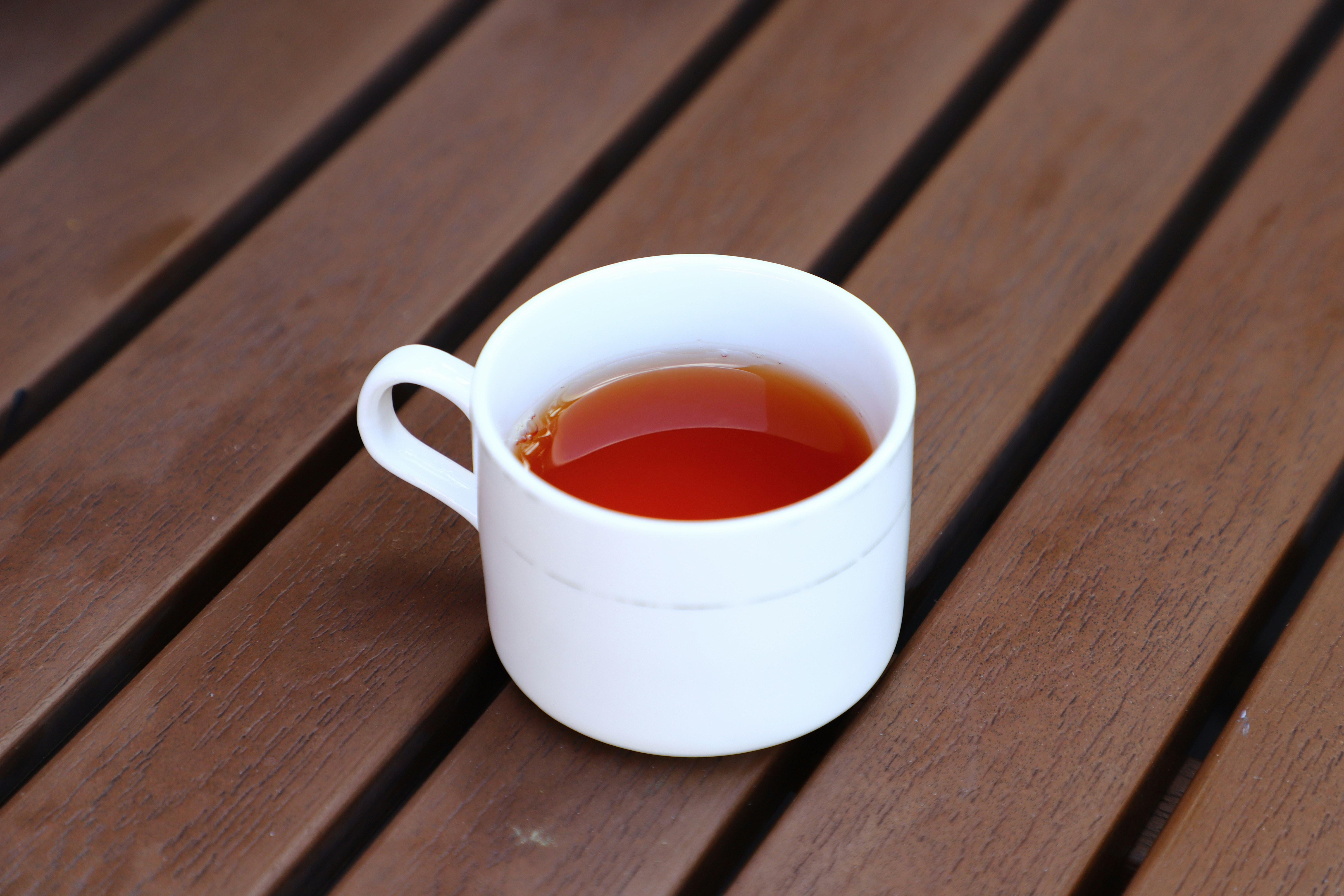 A white cup of tea on a wooden table