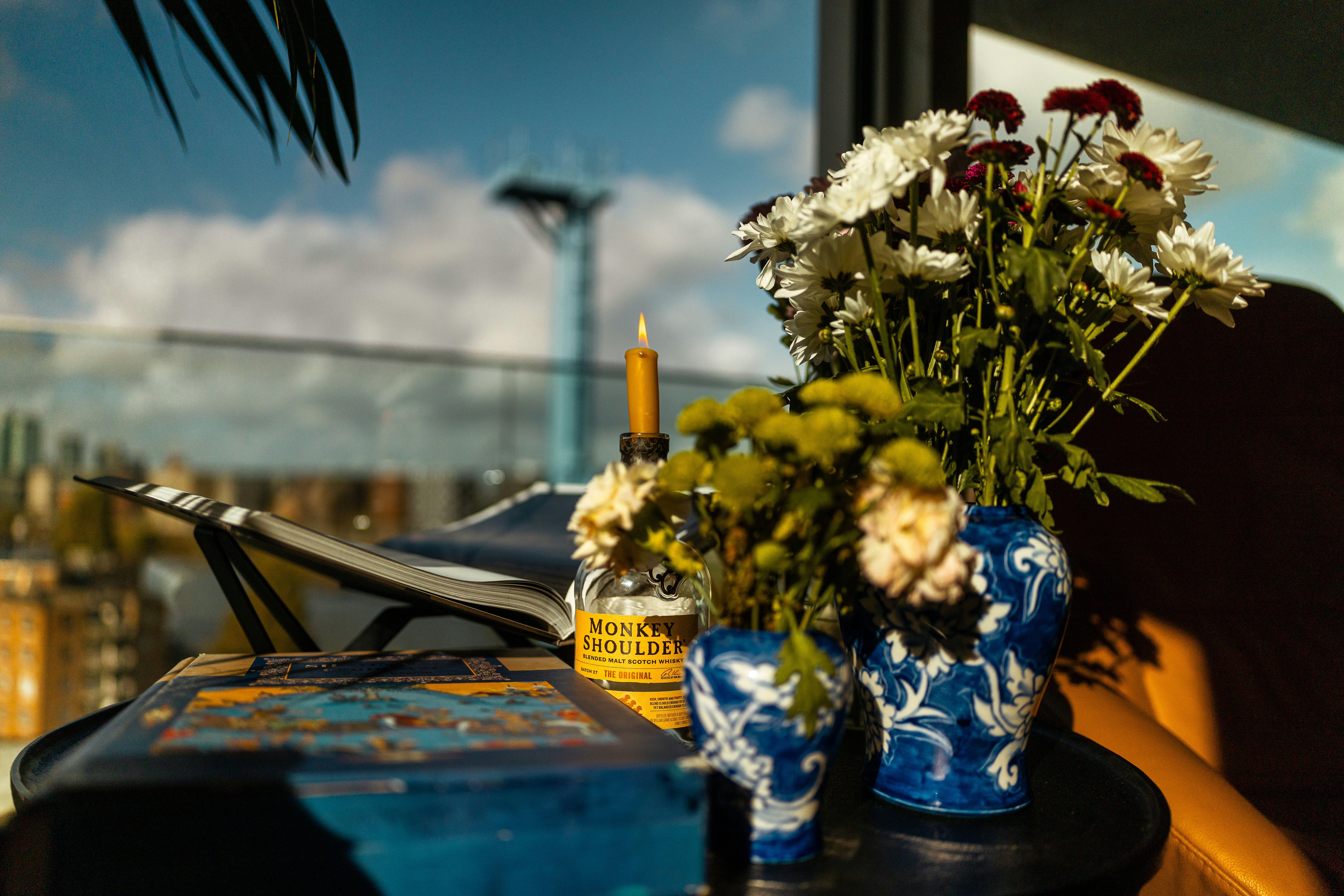 Flowers in vases on a table with city view.