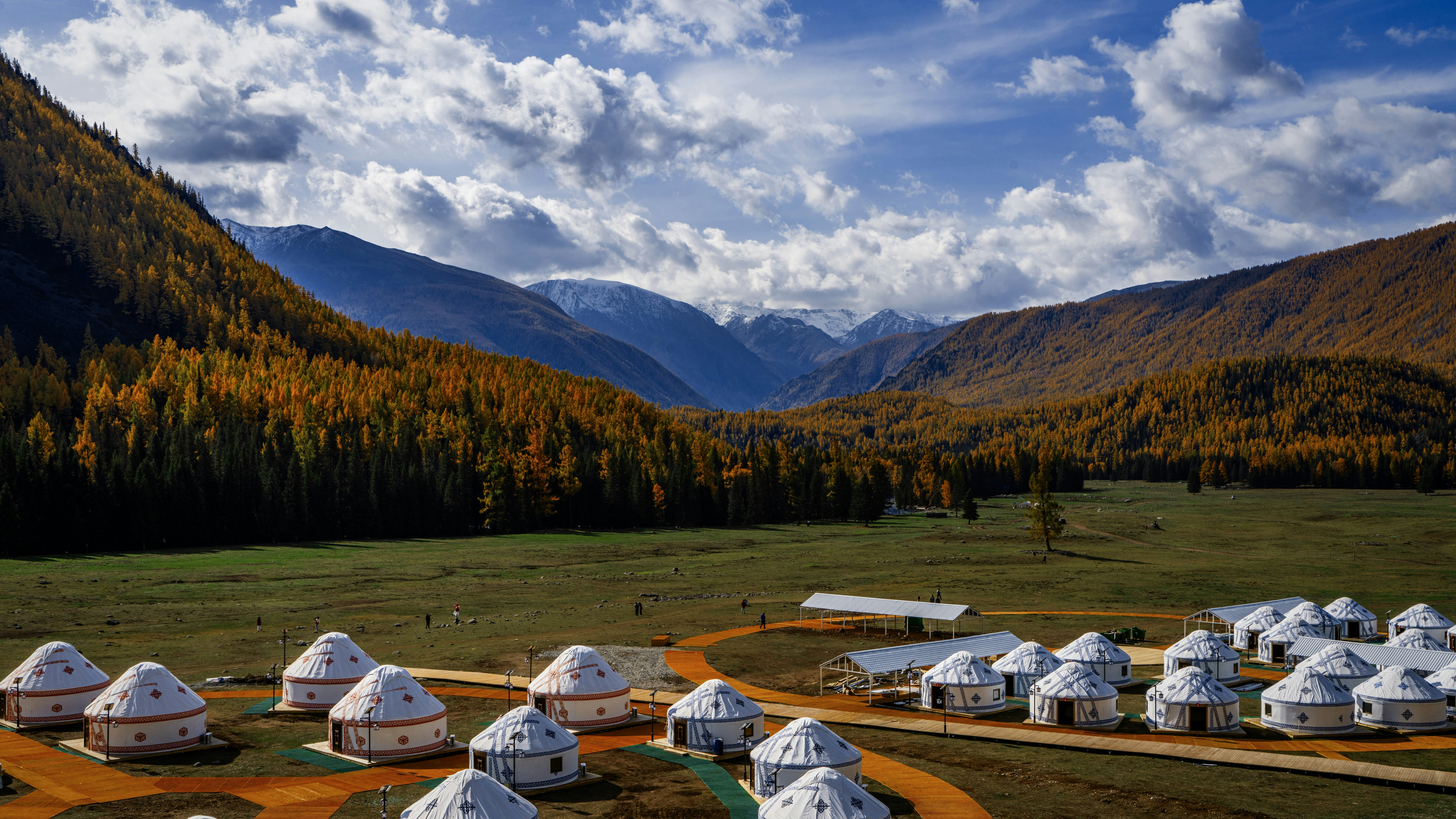 Yurt village nestled in a valley with autumn trees.