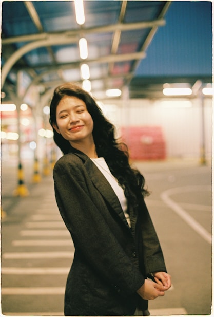 Young woman in blazer smiles outdoors at night