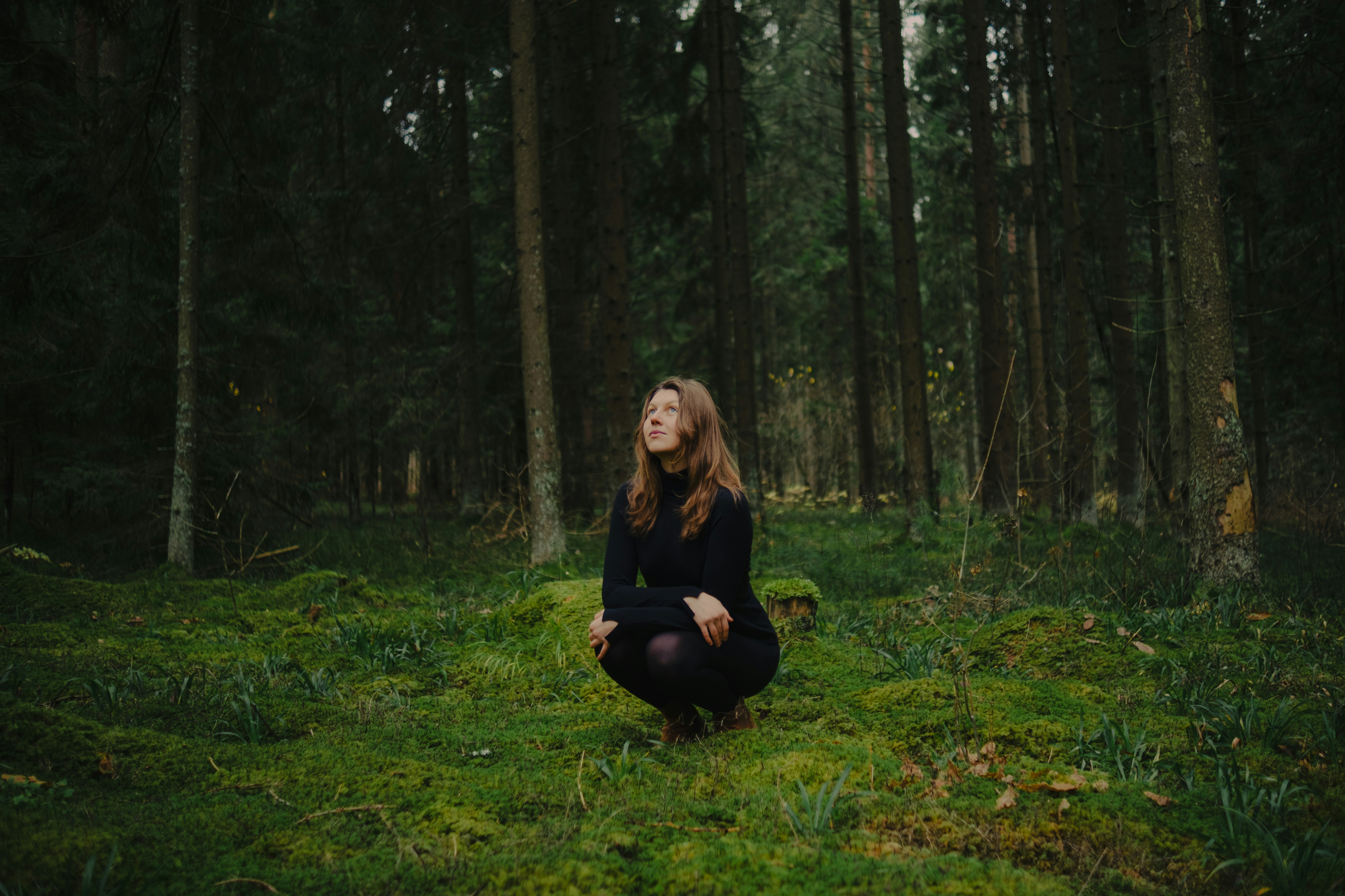 Young woman crouching in forest