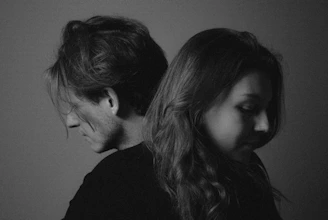 Two people standing back to back, looking down.