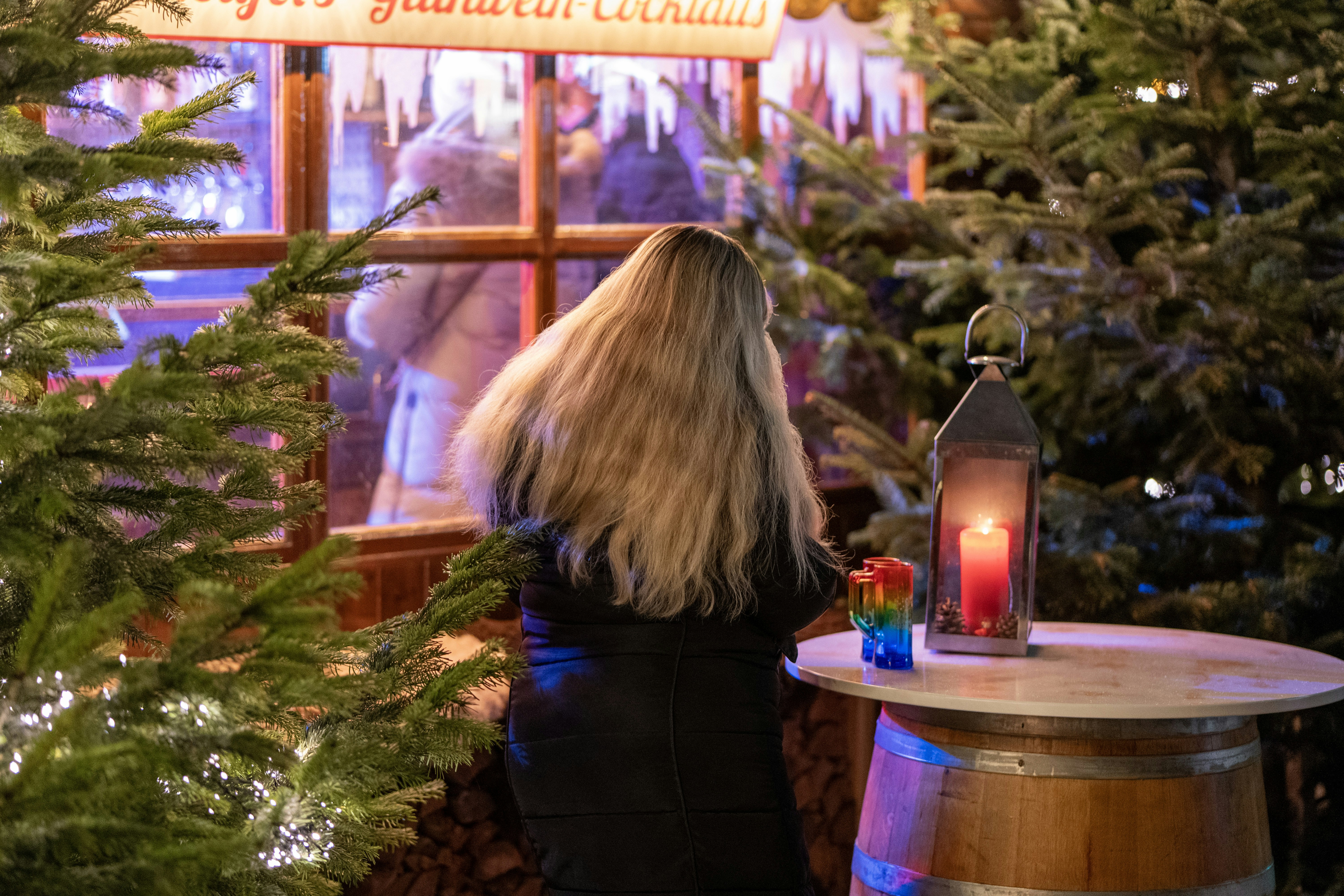 Woman looking into illuminated christmas market stall.
