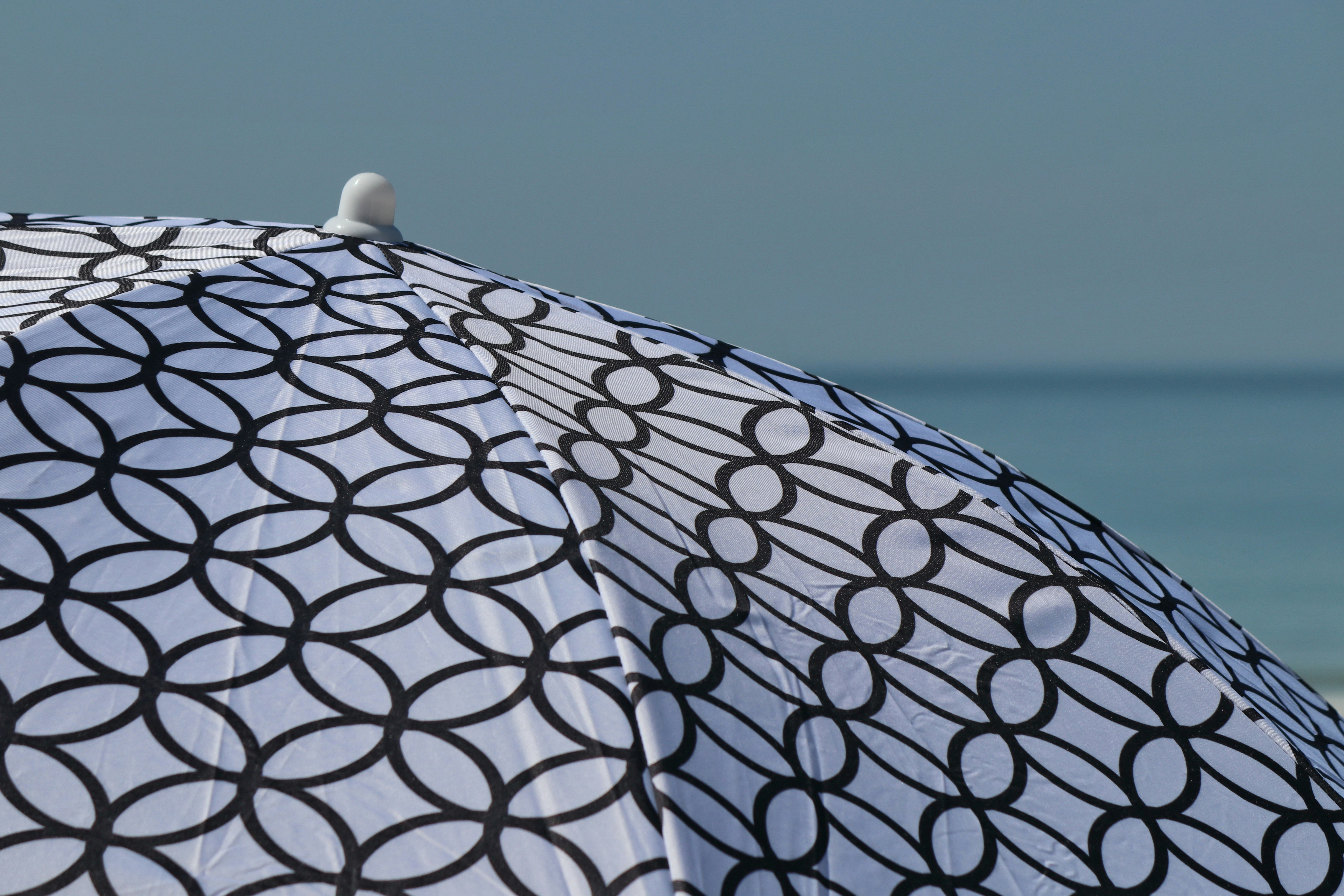 Patterned umbrella on a beach with ocean background