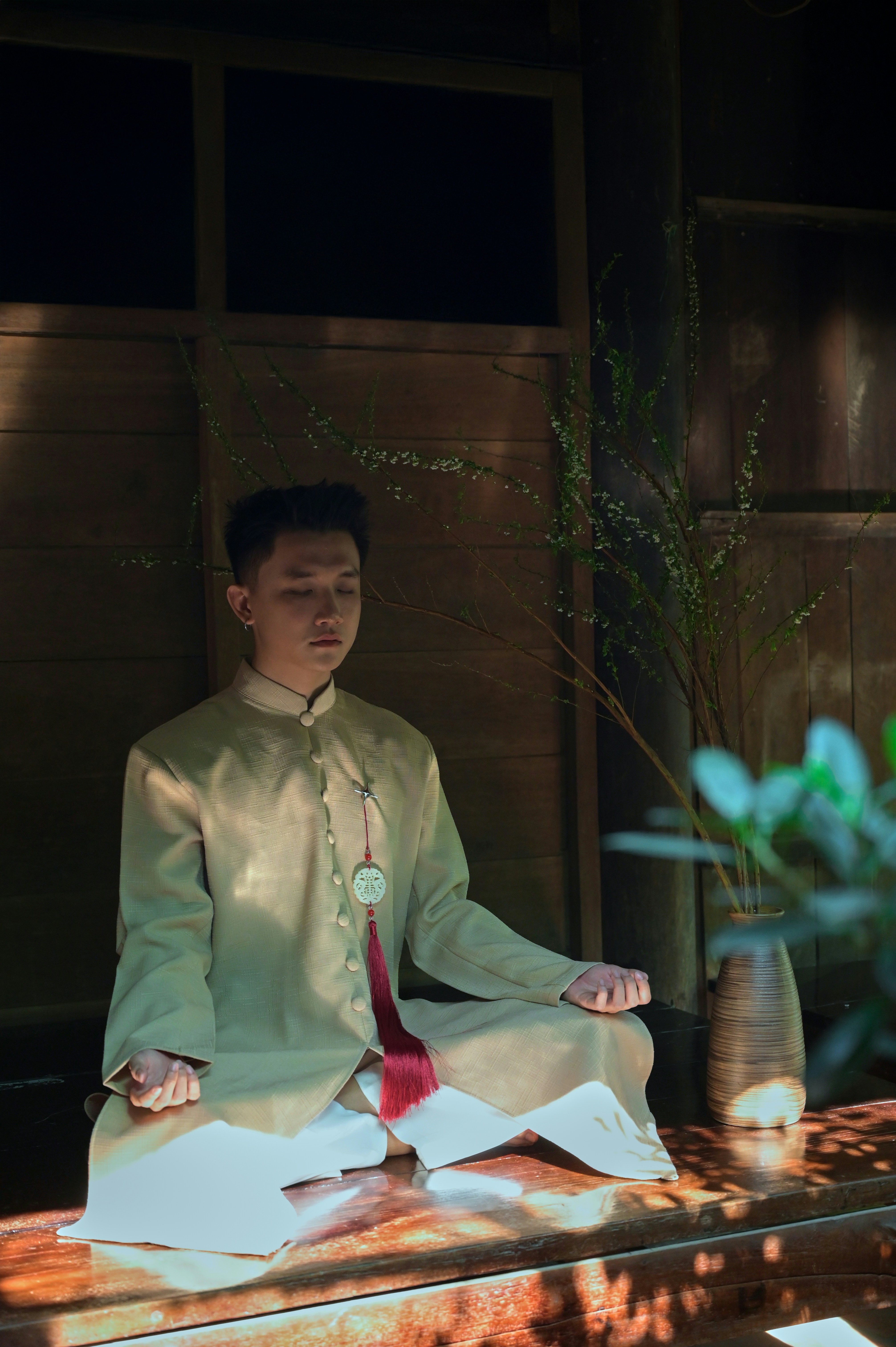 Man in traditional clothing meditating peacefully indoors.