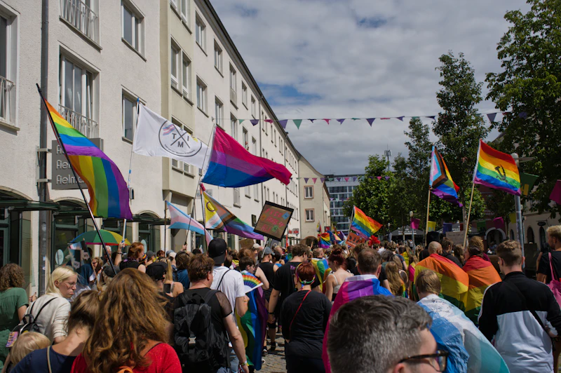A street crowd marching with rainbow and bisexual pride flags at a pride parade (generic pride-parade photo, not verifiably Chicago's)