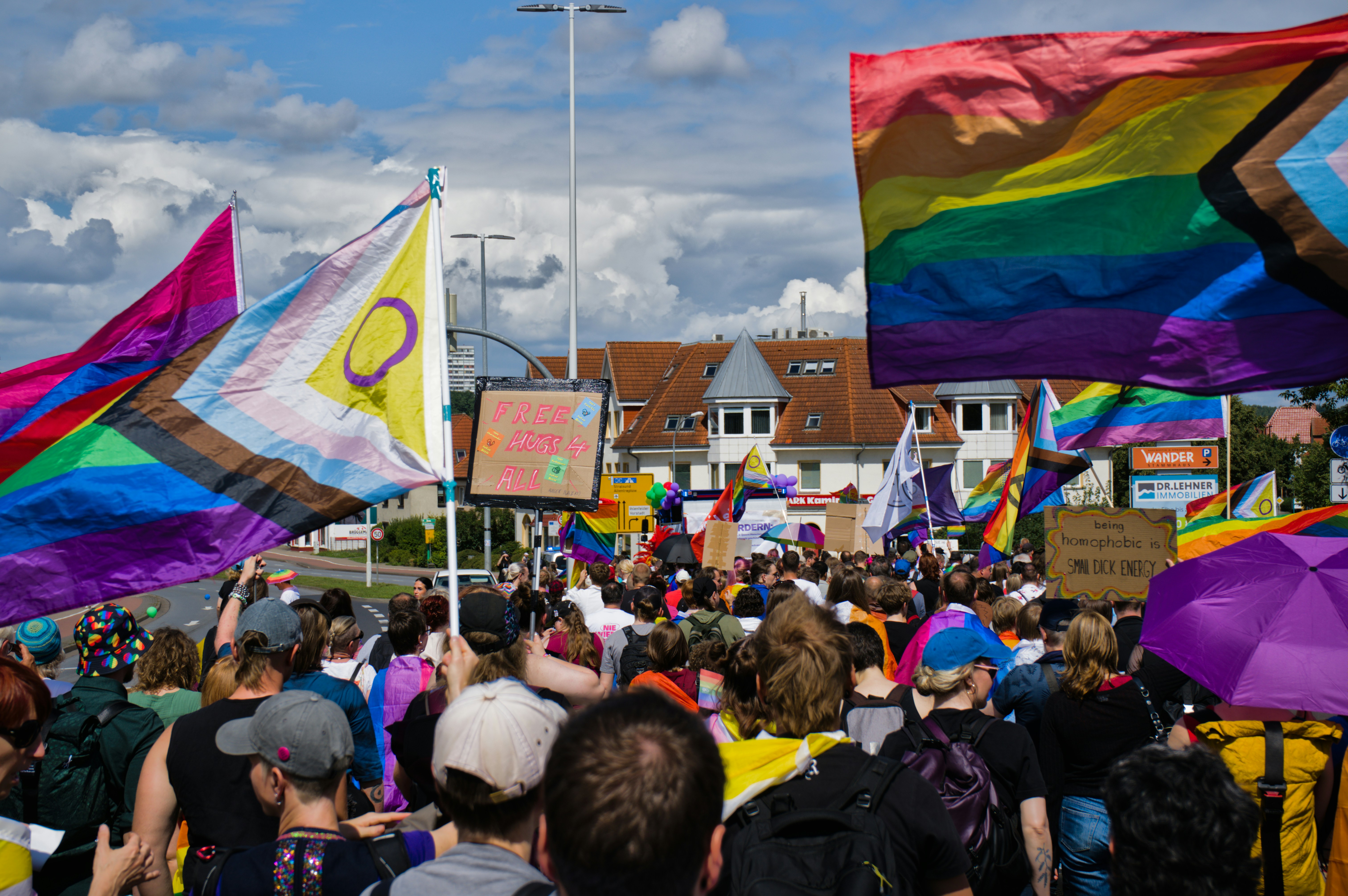 La gente desfila con banderas del orgullo bajo un cielo nublado