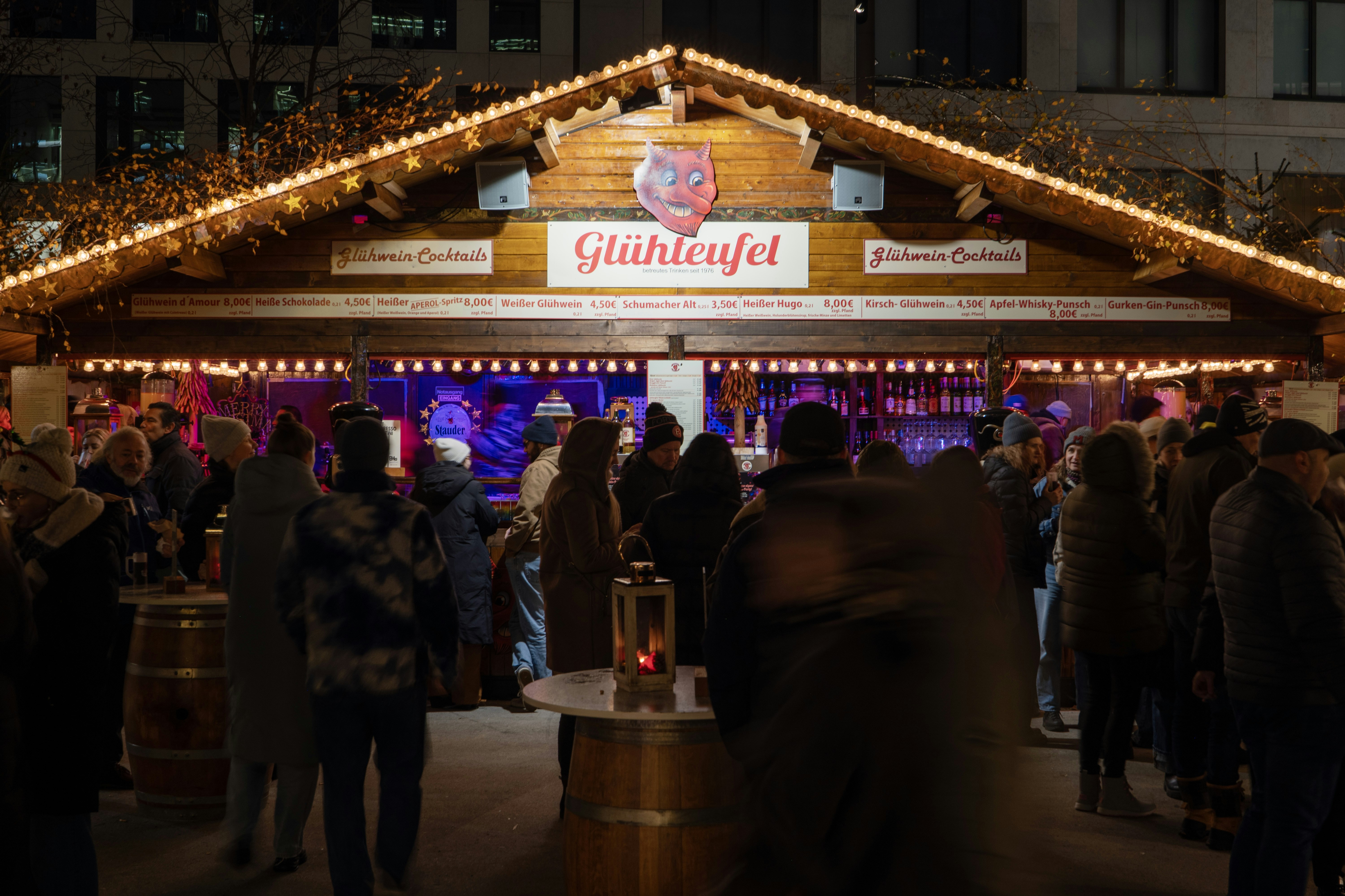 People gather at a festive wooden stall at night
