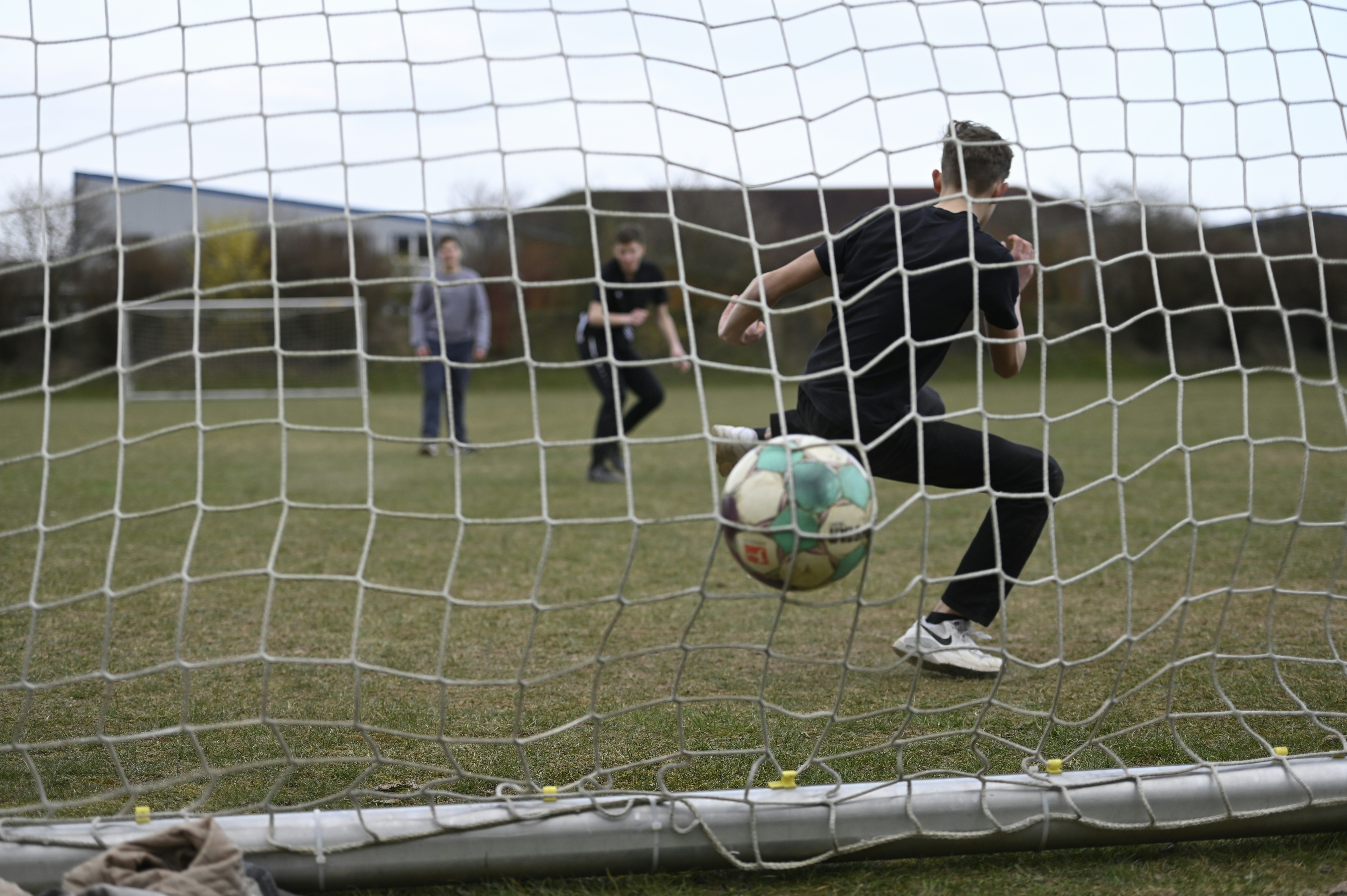 Teenagers playing soccer on a grassy field