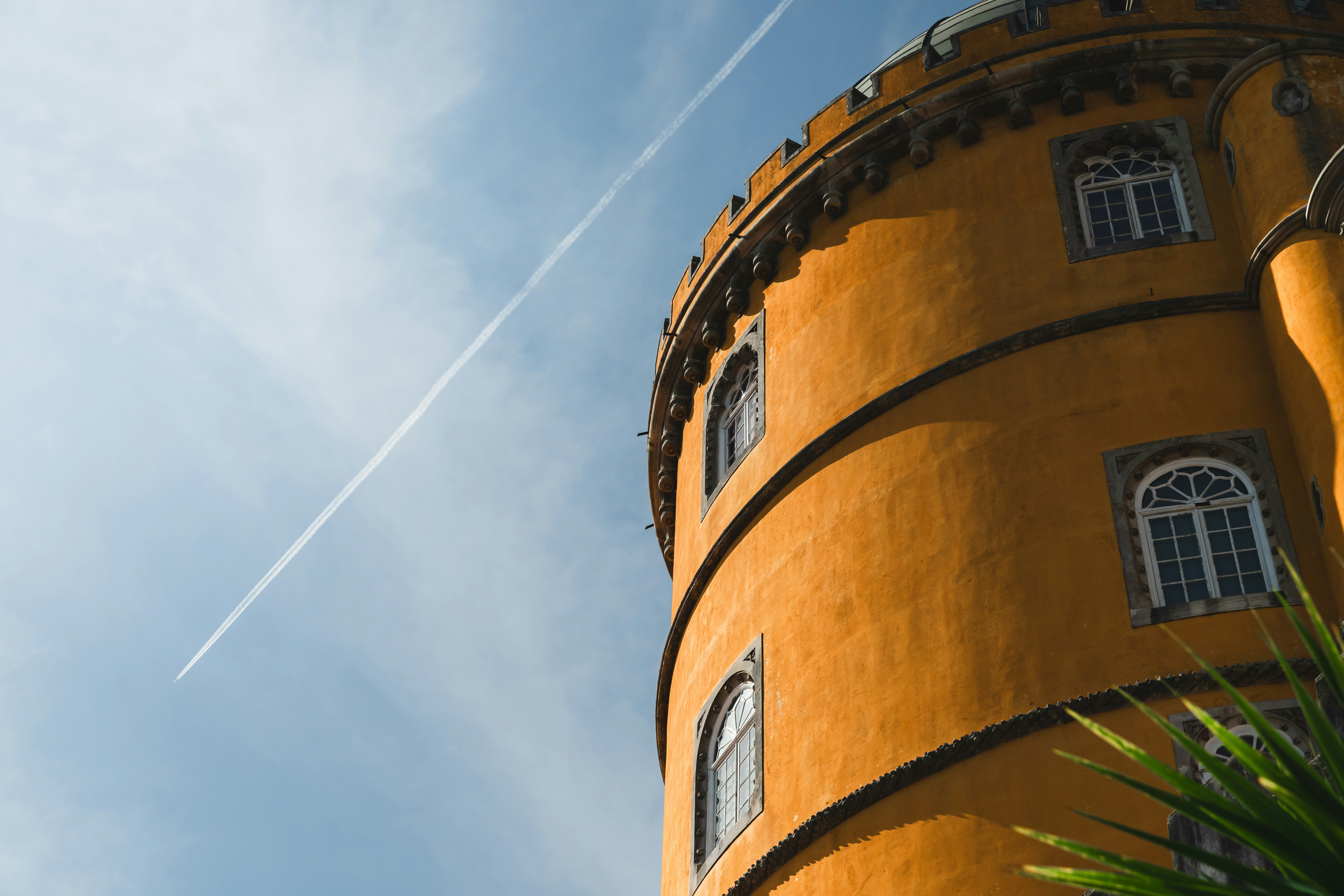 Orangefarbener Turm mit Fenstern vor blauem Himmel