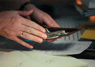 Hands holding cash in a wallet over papers