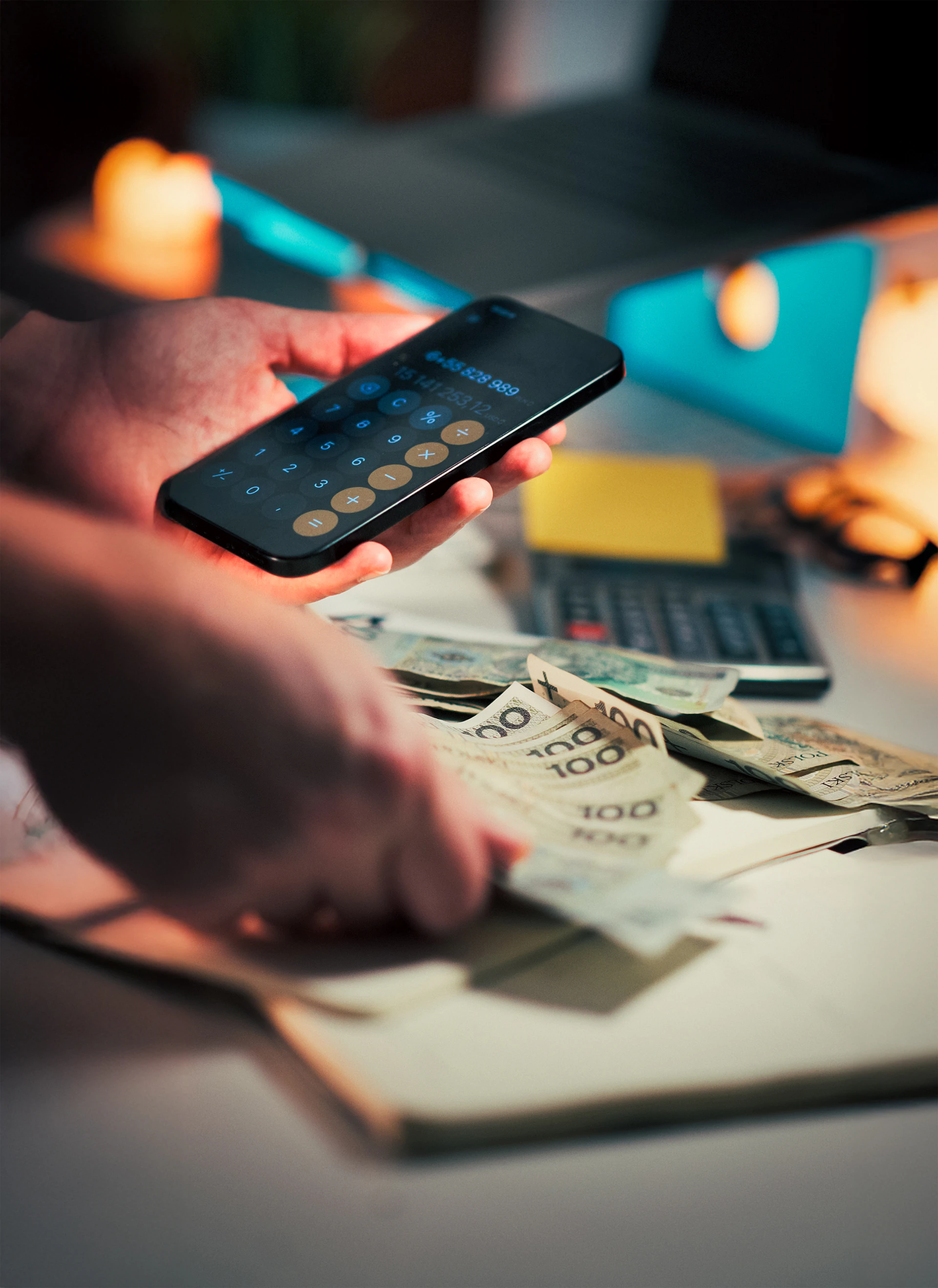 Hands holding money and using calculator on phone.