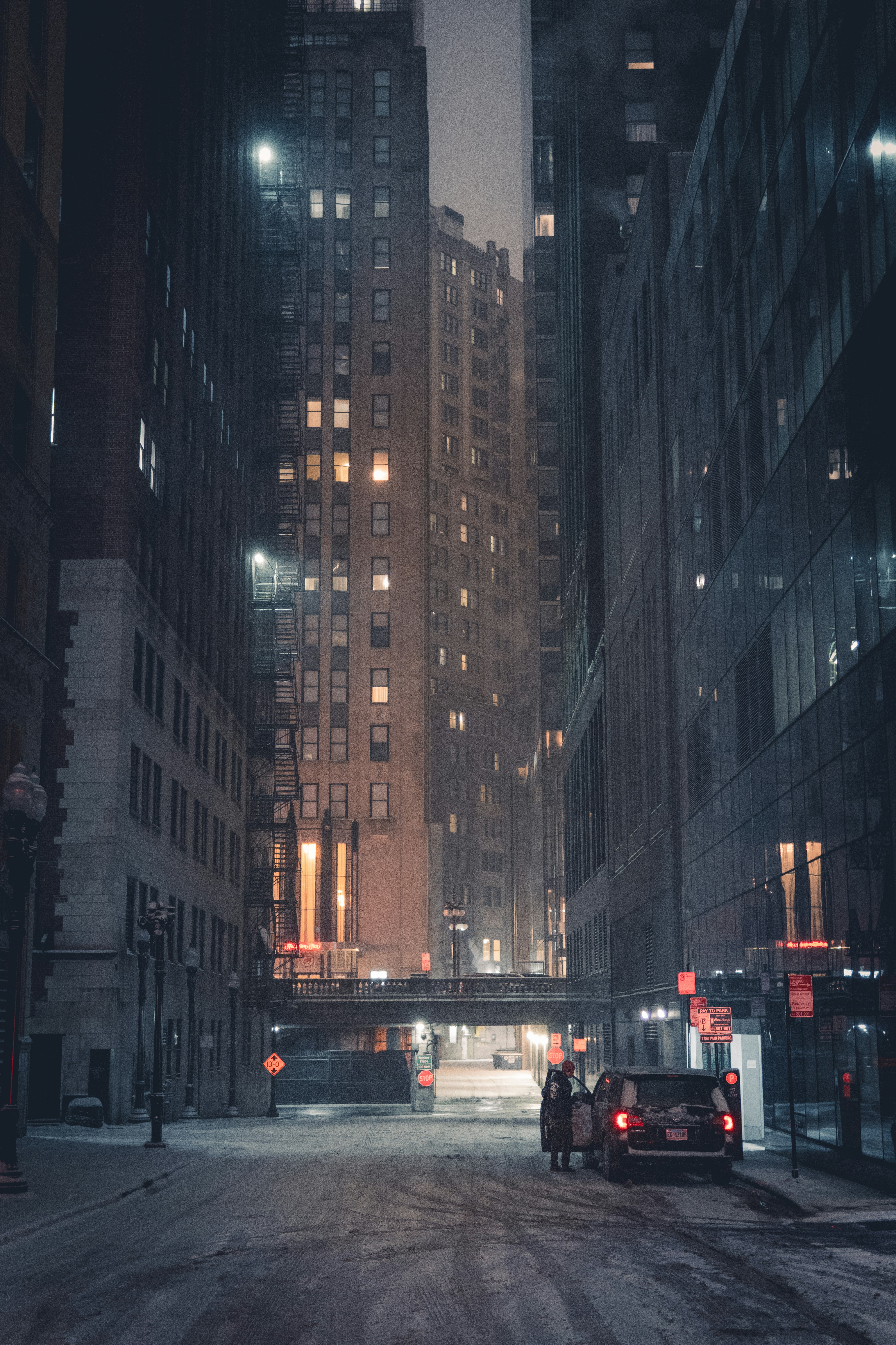 Photo of City street at night with tall buildings and car. by Tobias Reich
