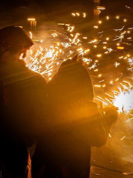 Two people watch fireworks explode in the night sky.