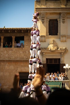 People form a human tower against a building.