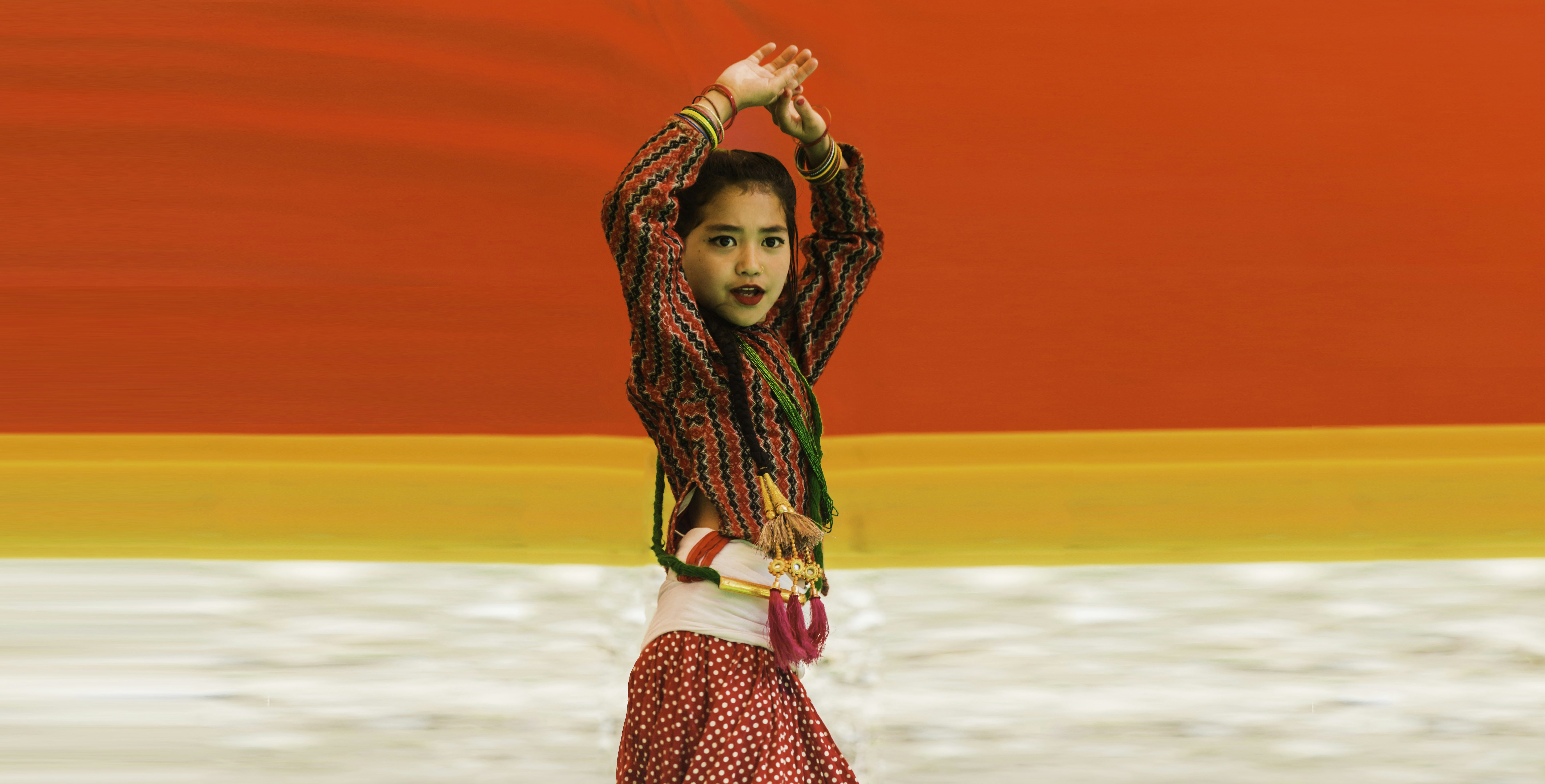 Ein junges Mädchen in traditioneller Kleidung tanzt fröhlich.