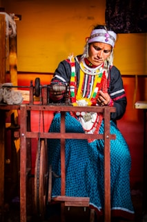 Woman spinning yarn on a traditional wooden wheel.