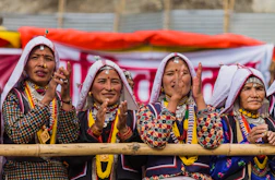 Four women in traditional clothing clapping