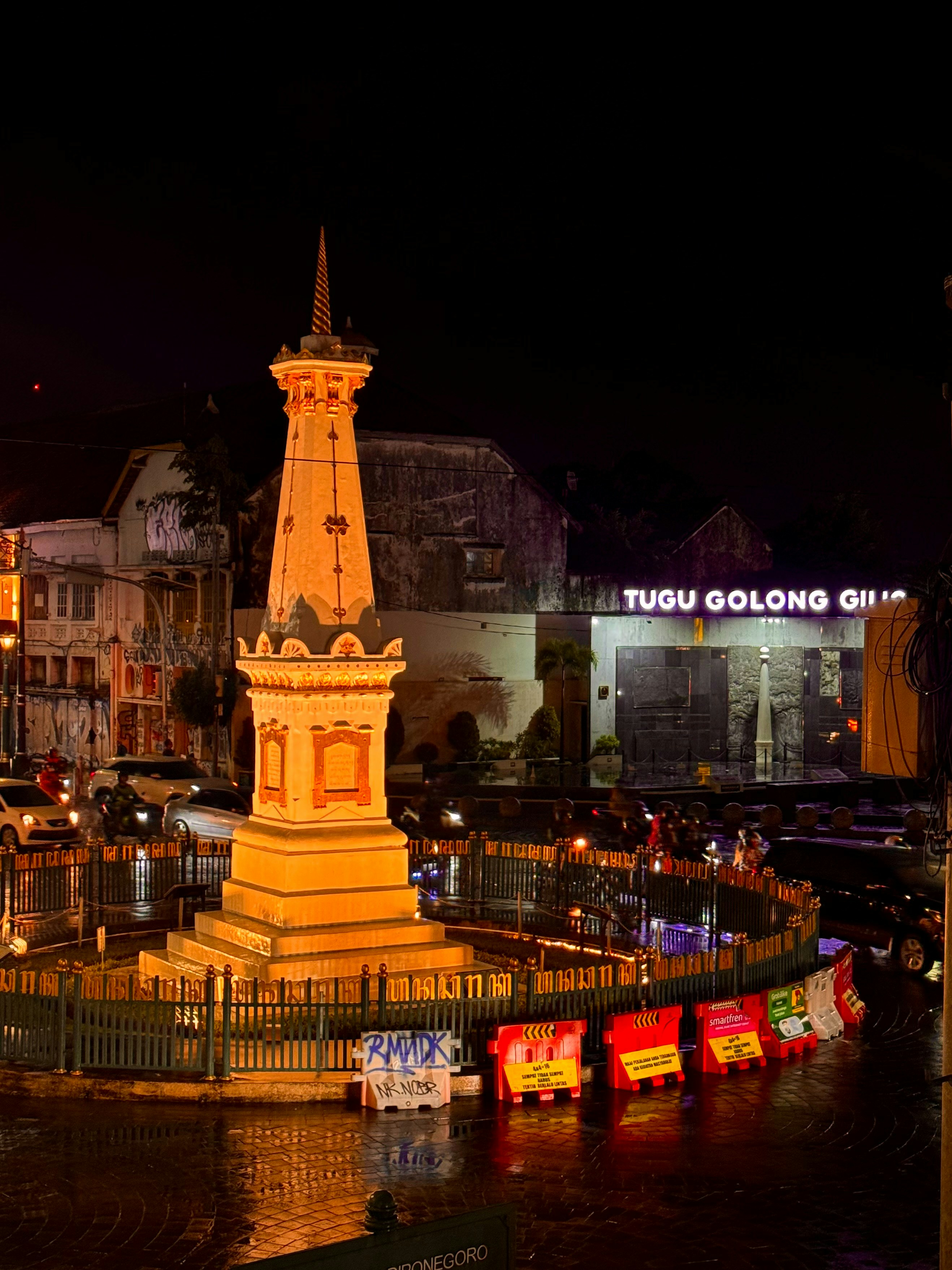 A monument at night with traffic and lights.