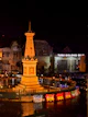 A monument at night with traffic and lights.