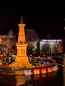 A monument at night with traffic and lights.