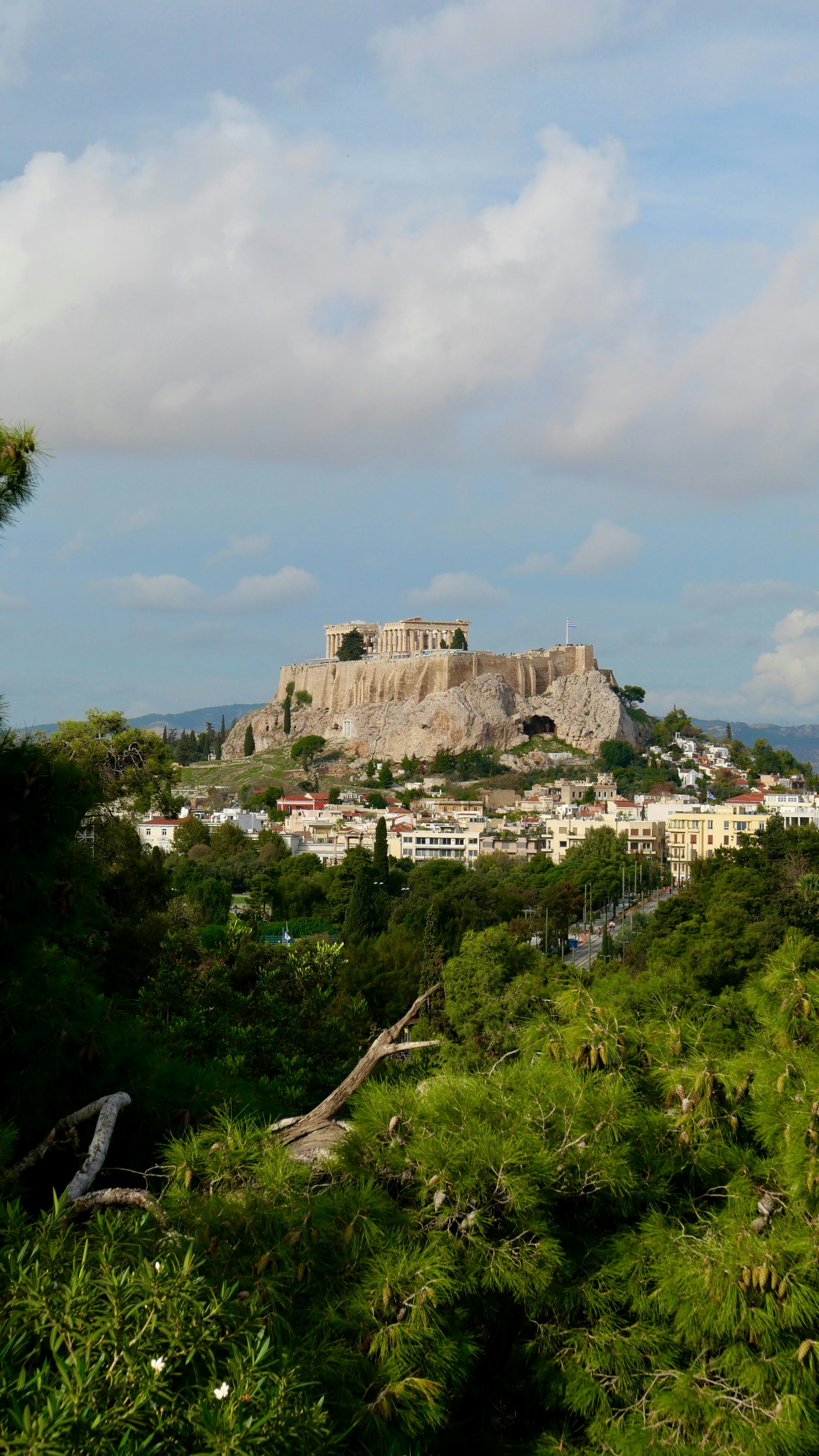 Ancient acropolis ruins atop a hill overlooking a city.