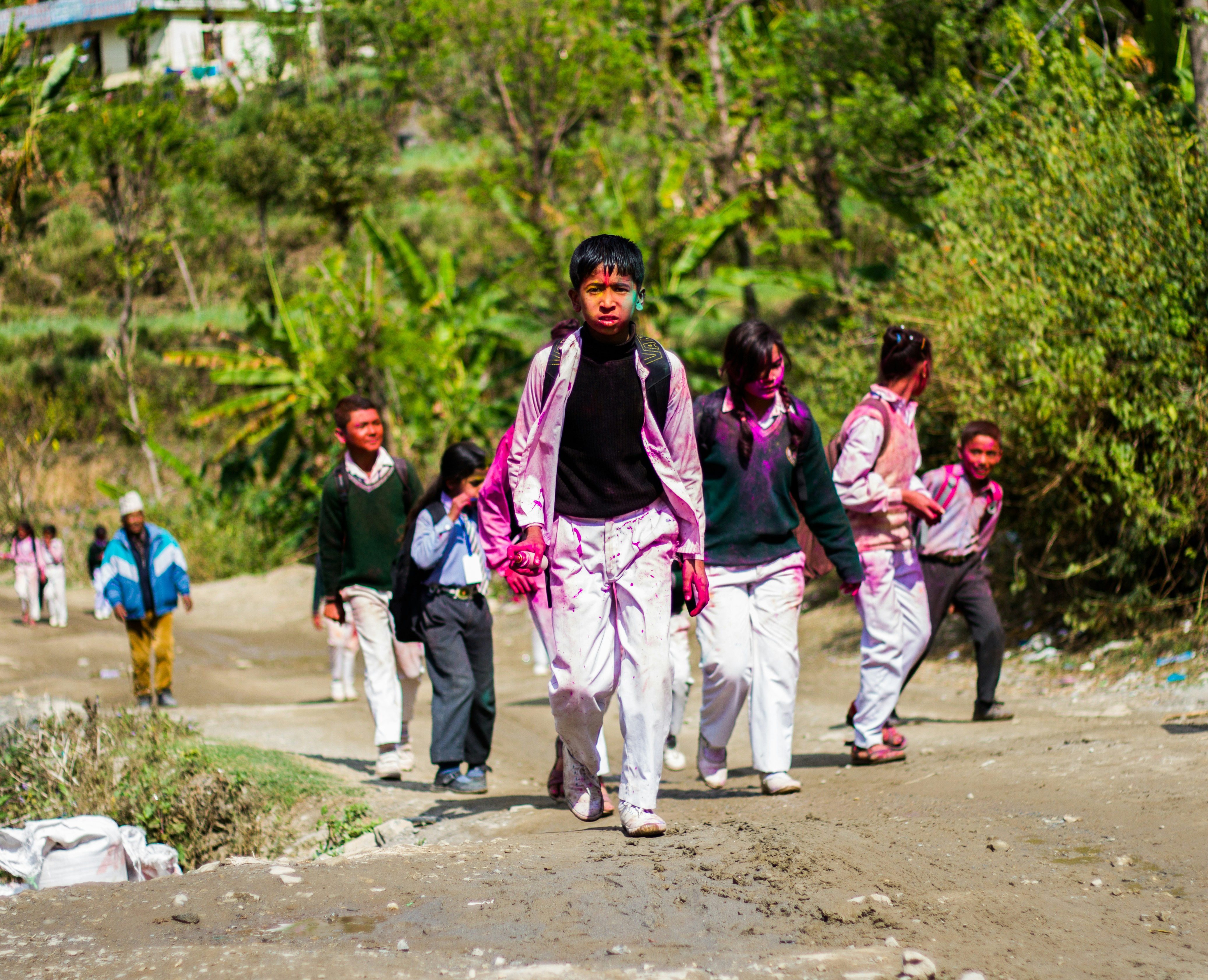 Children with colorful powder walking on a dirt road.