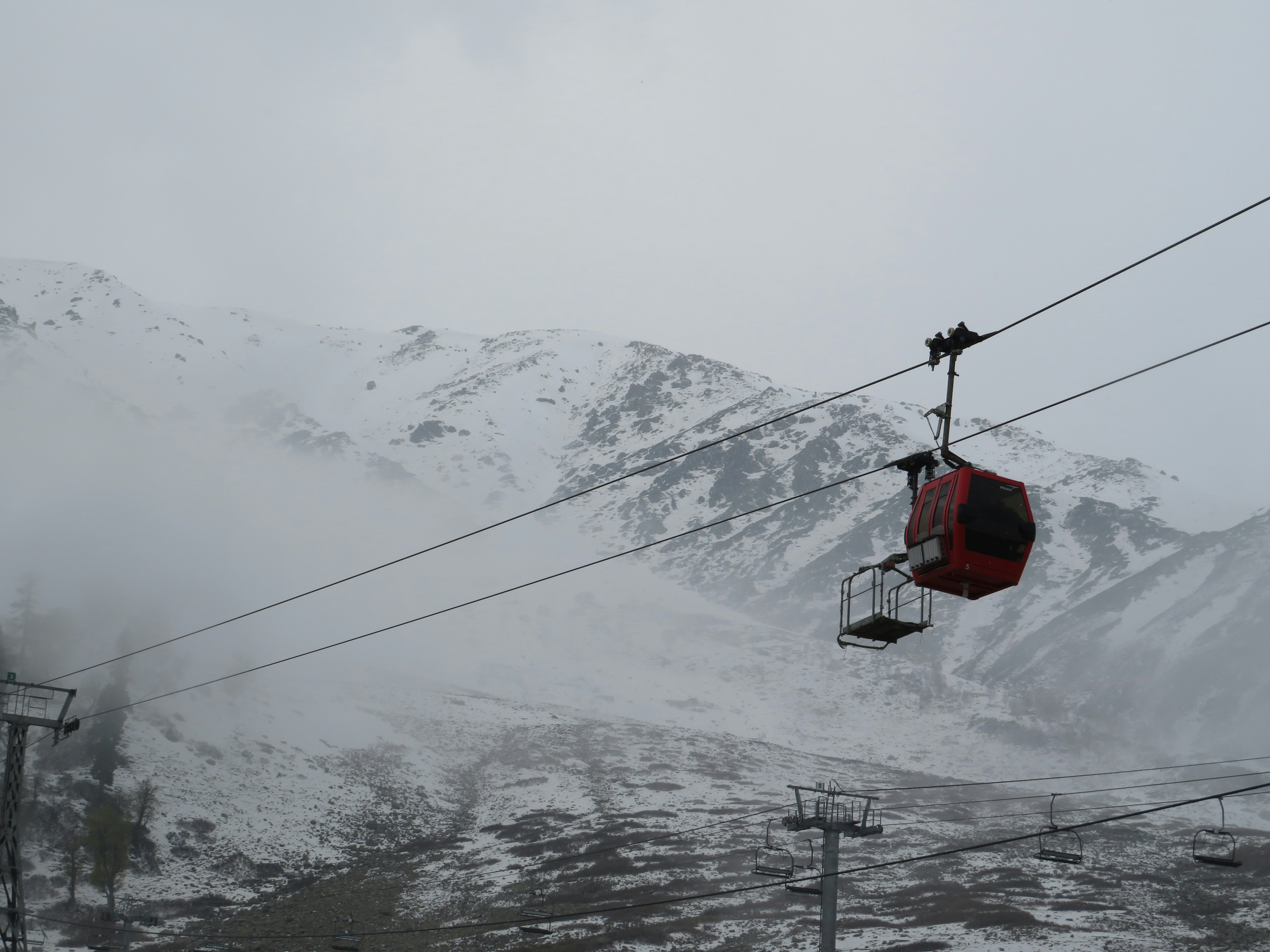 Red cable car on snowy mountain slope
