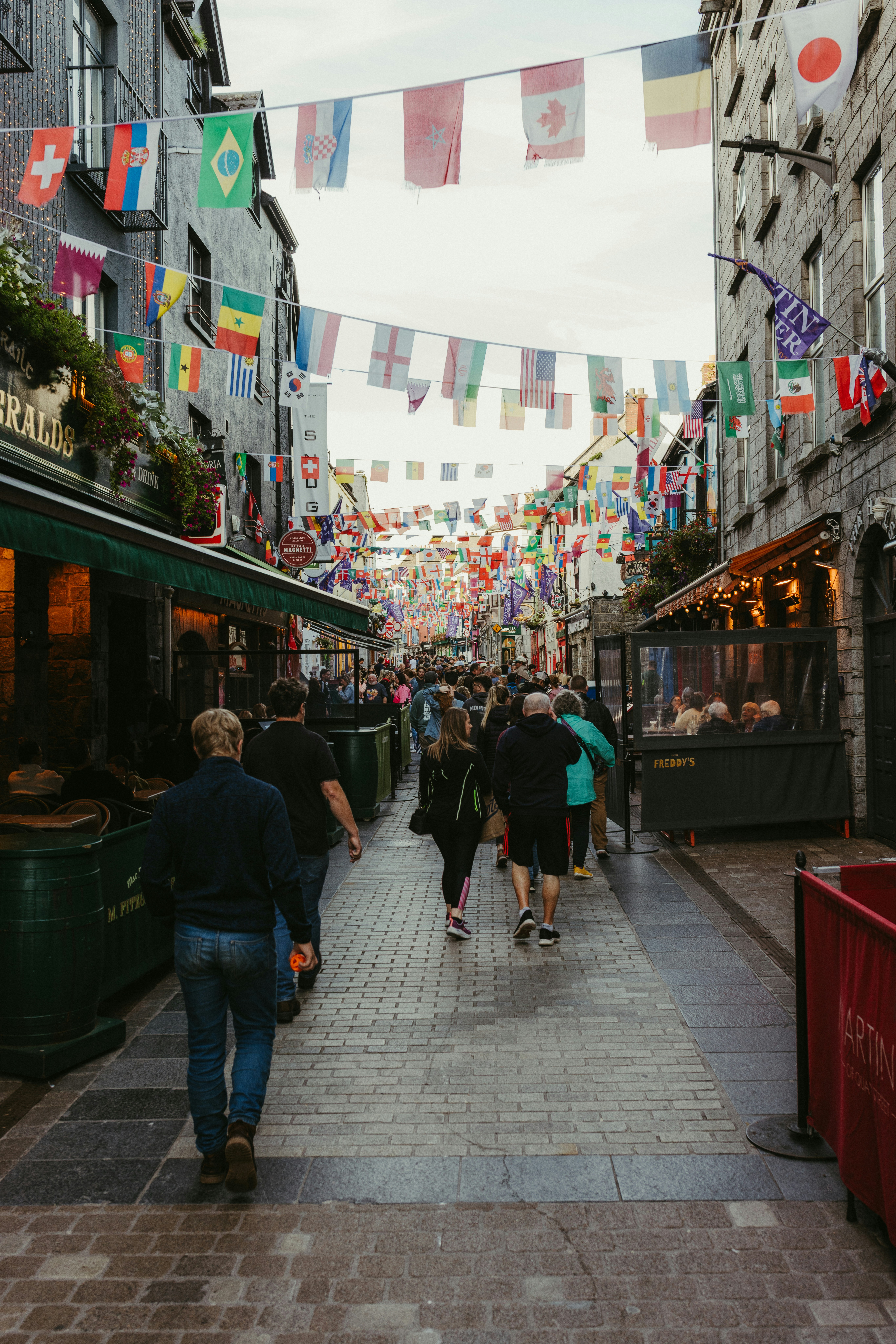 People walking down a street decorated with flags.