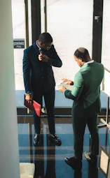 Two businessmen in suits discussing documents indoors