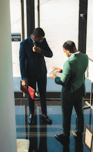 Two businessmen in suits discussing documents indoors
