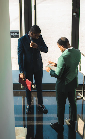Two businessmen in suits discussing documents indoors