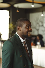 A smiling black man in a green suit.