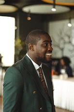 A smiling black man in a green suit.