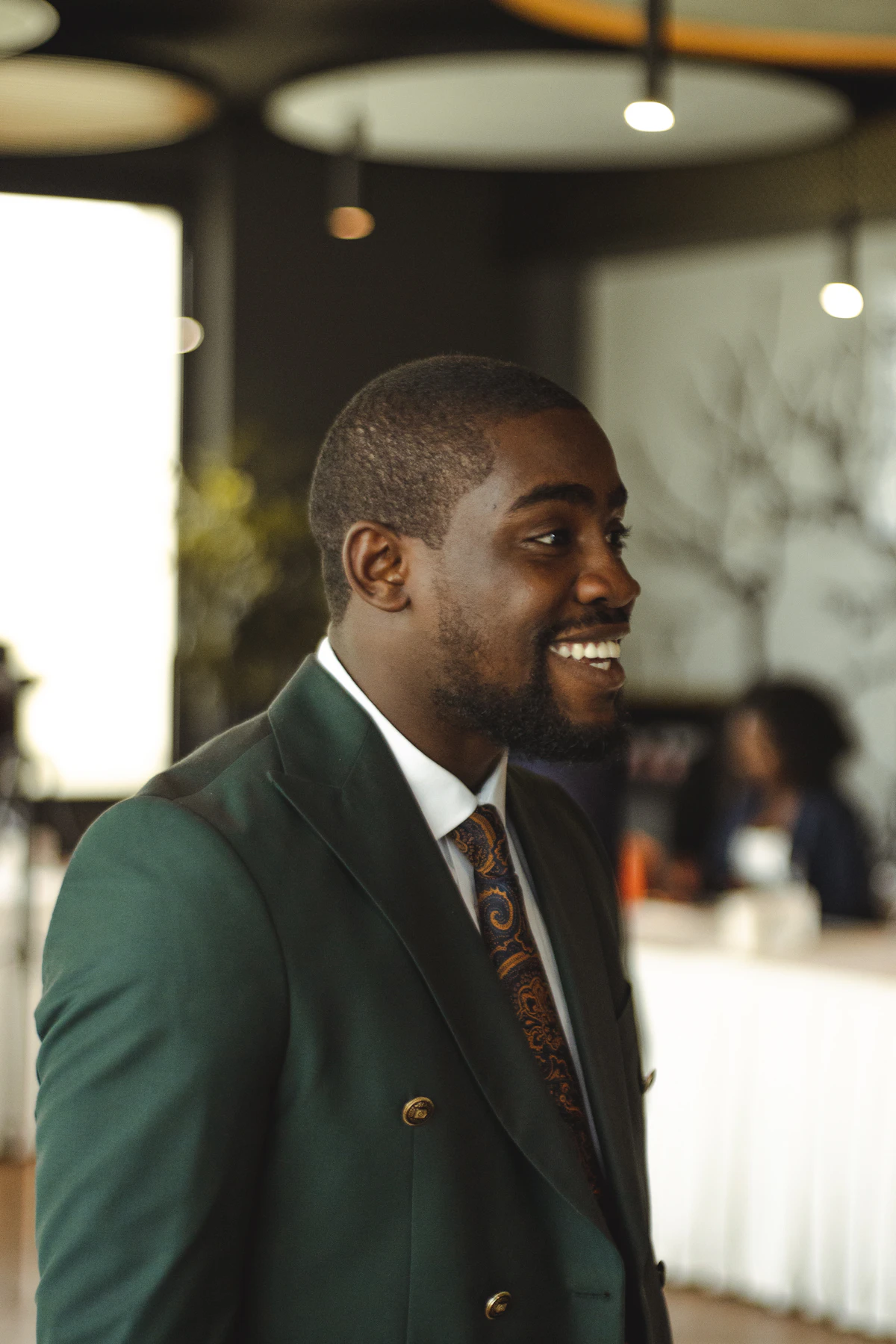 A smiling black man in a green suit
