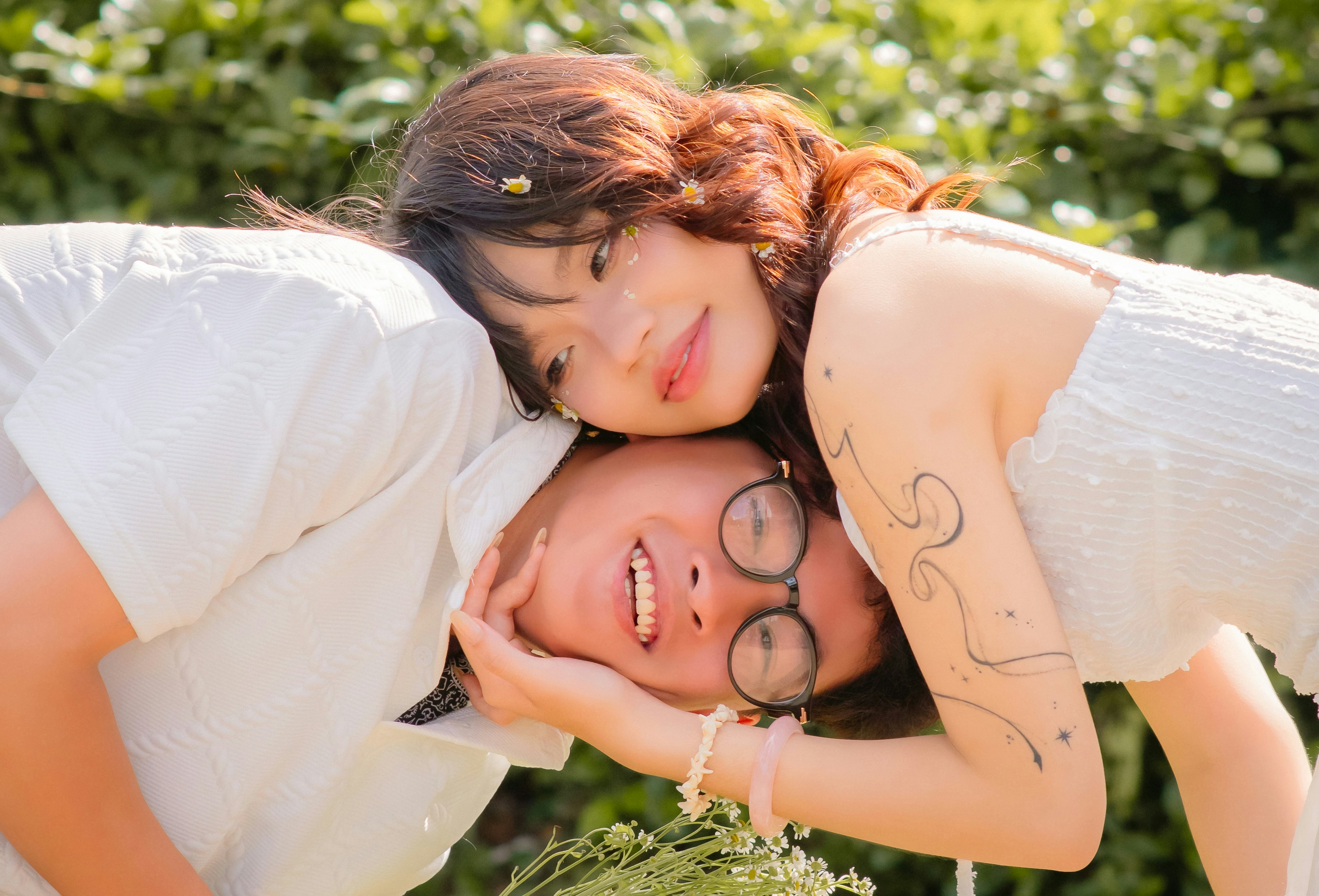 Pareja con ropa blanca apoyando la cabeza junta al aire libre