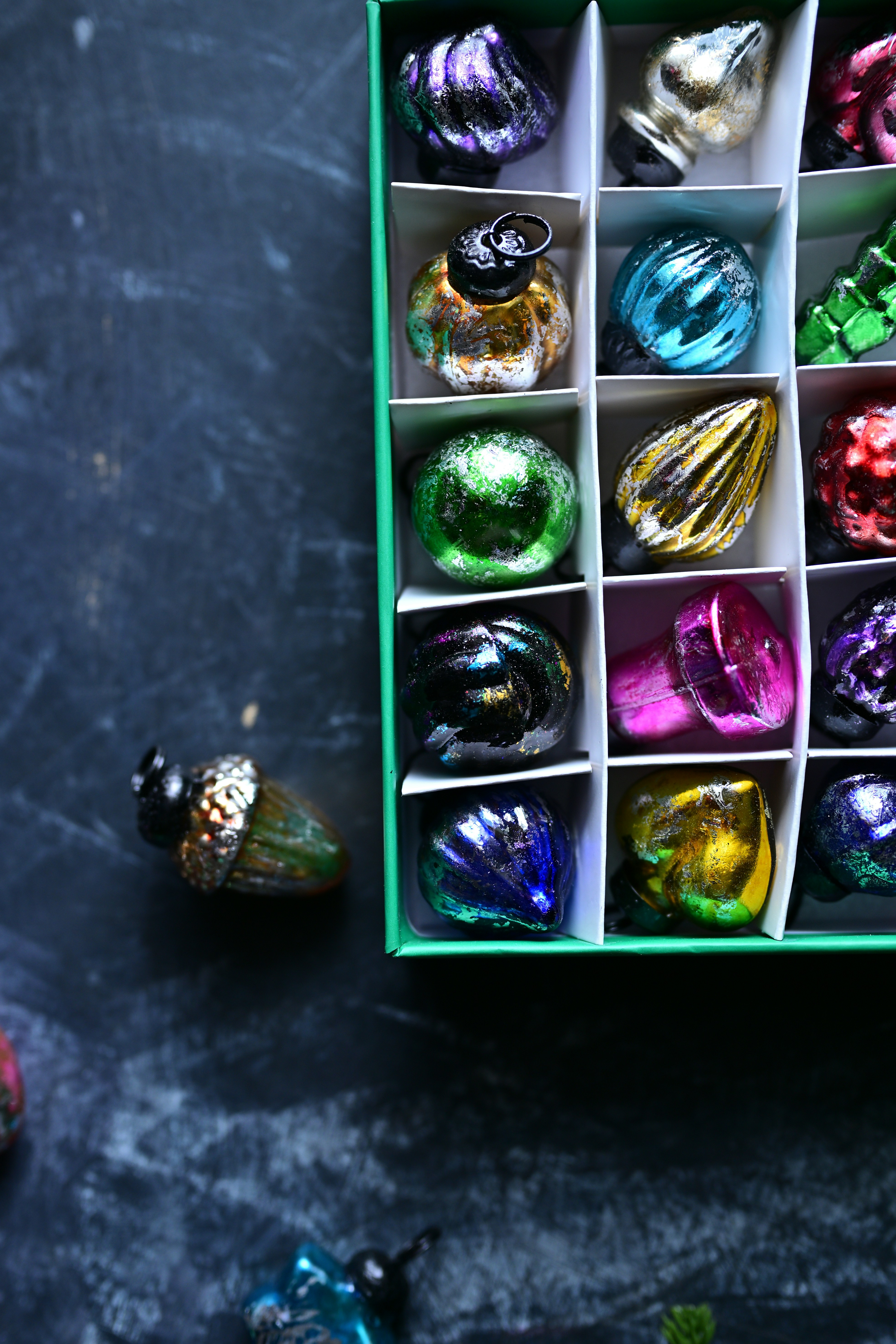 Small, colorful glass ornaments in a box.