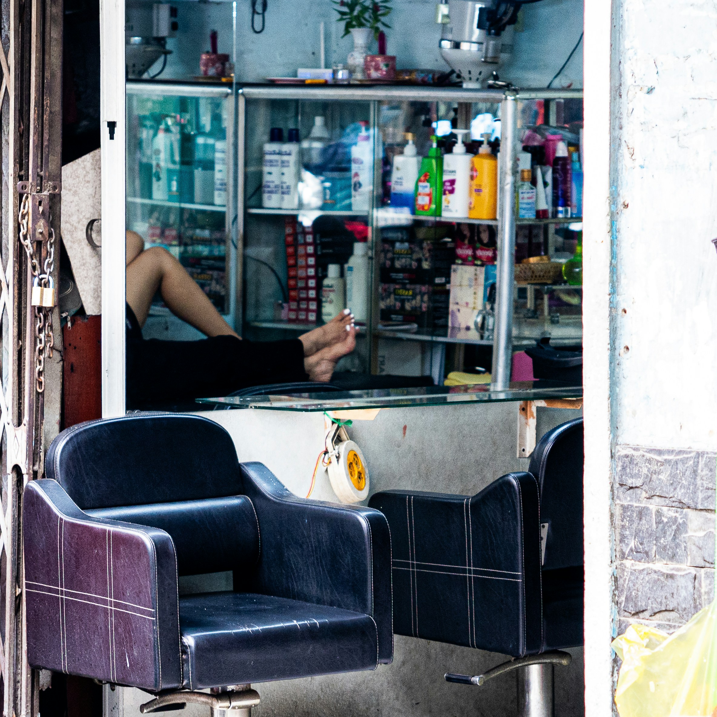 Two chairs outside a salon with products on shelves.