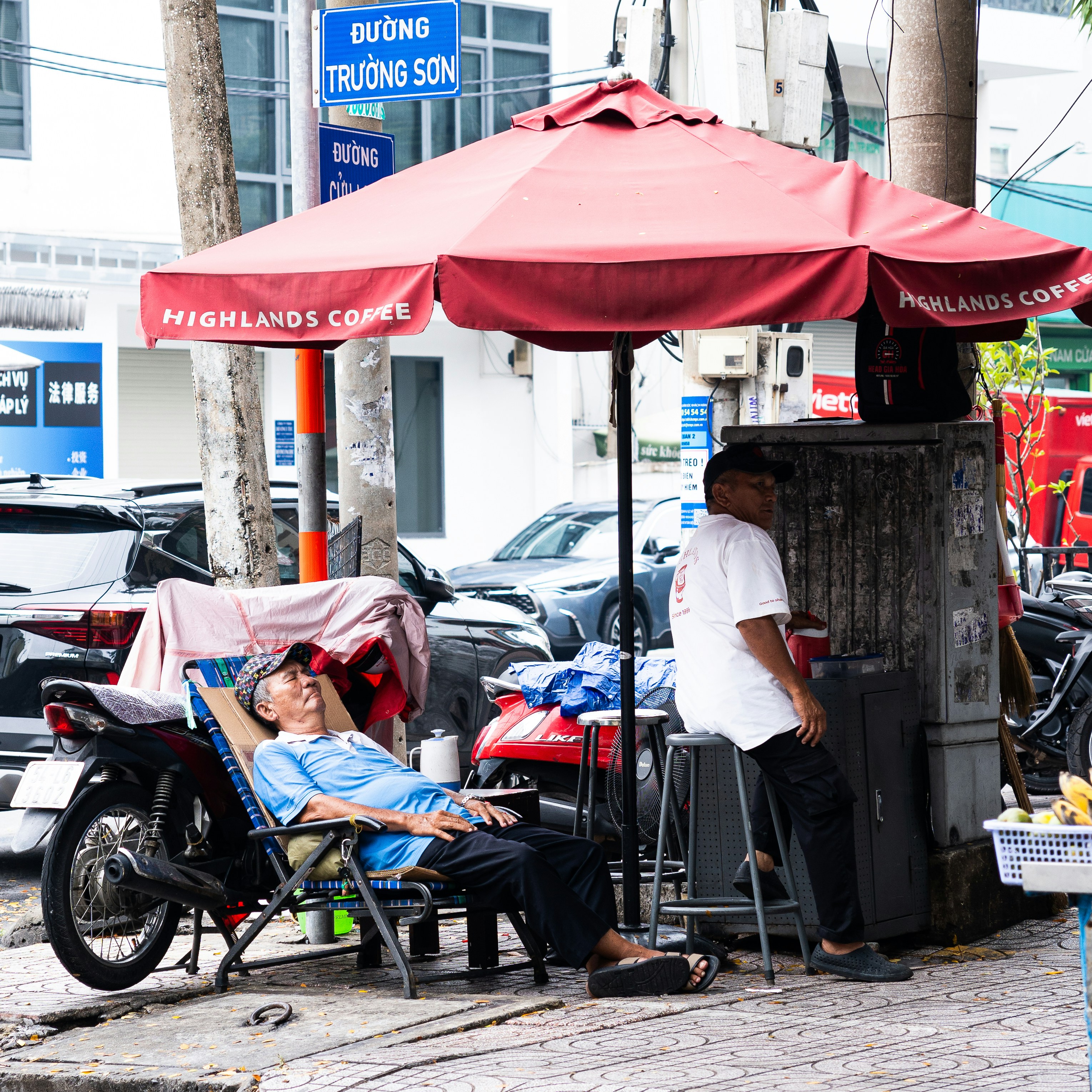 Hombre relajándose bajo un paraguas junto a una moto