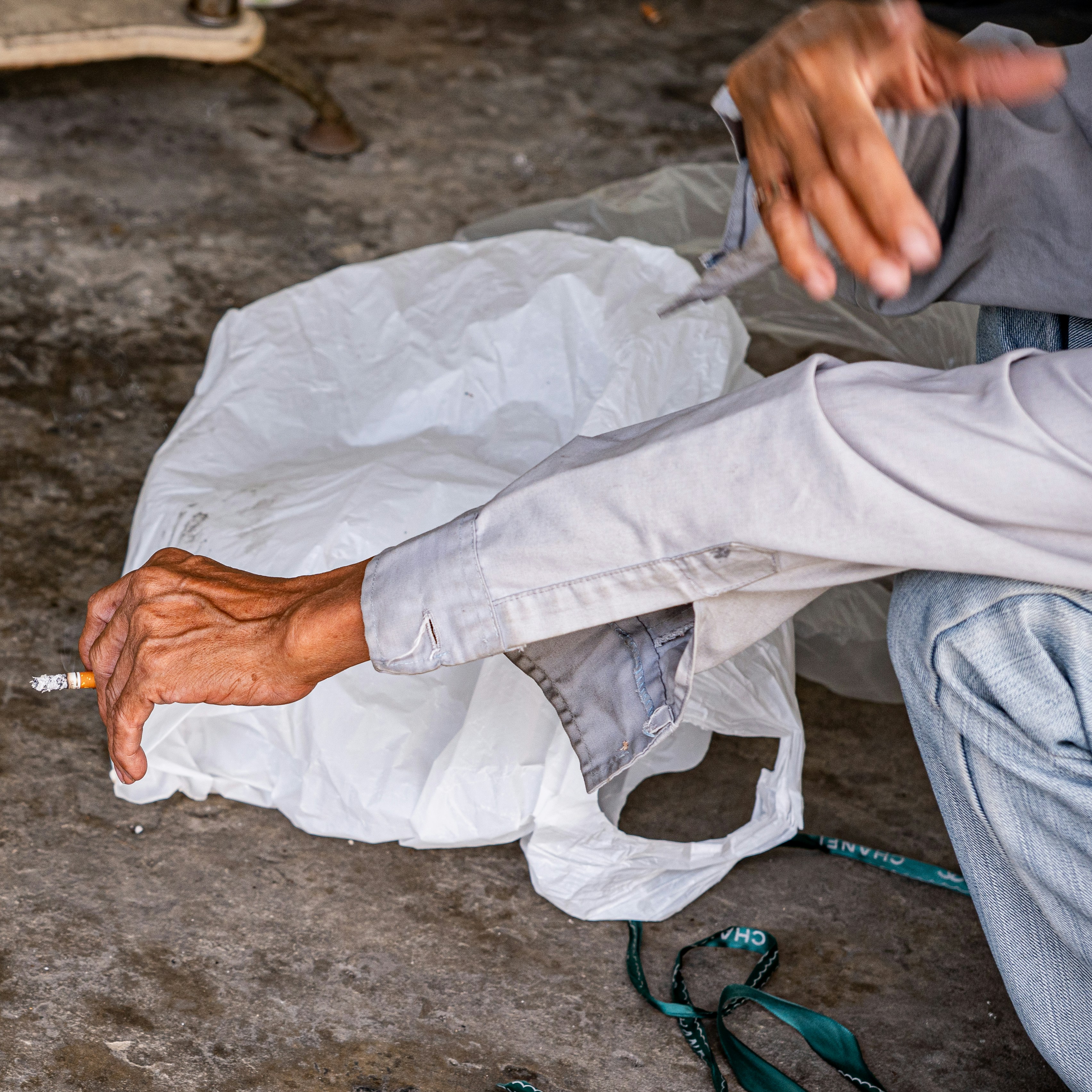 Person holding a cigarette and a white bag.