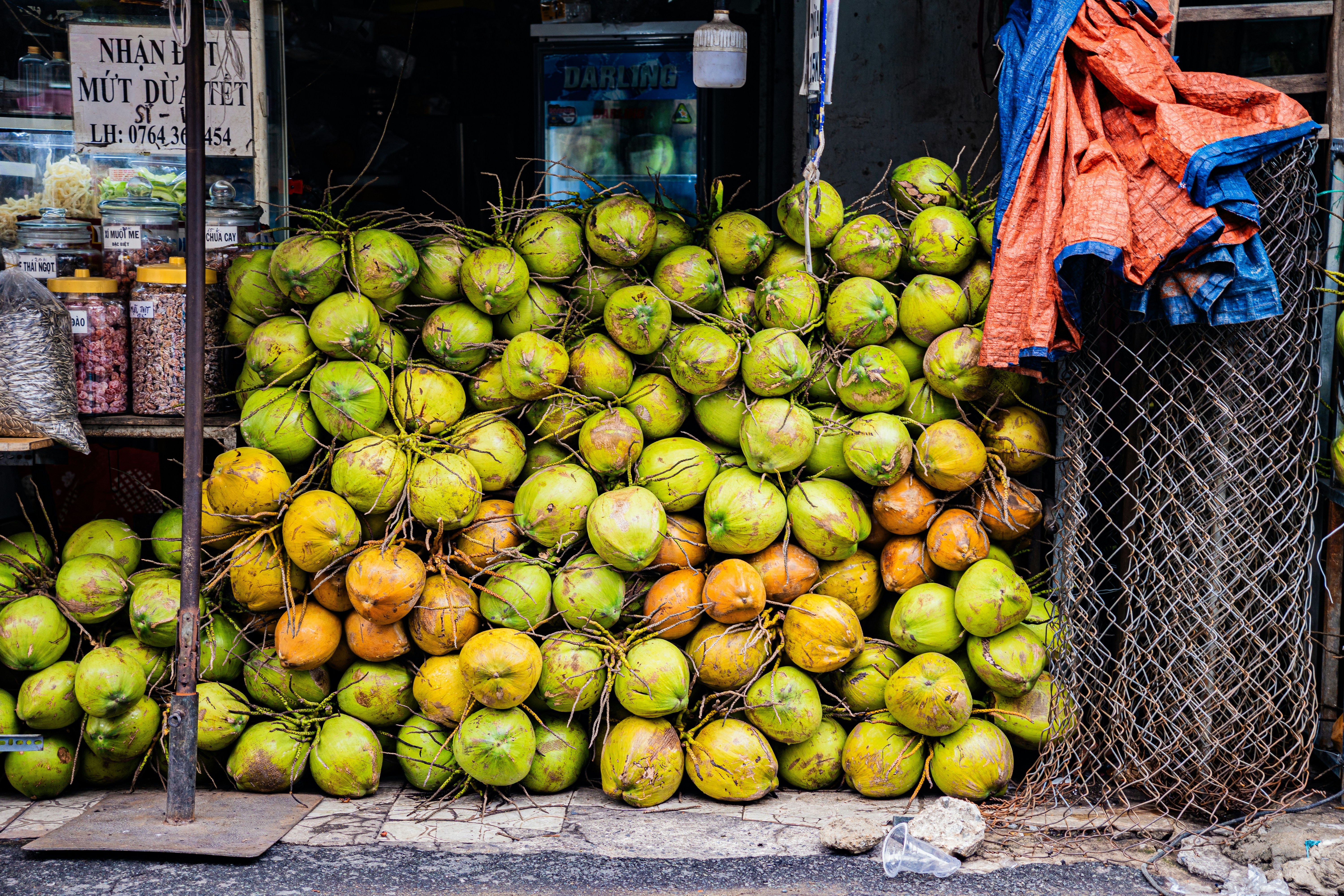 A large pile of fresh coconuts at a market stall.
