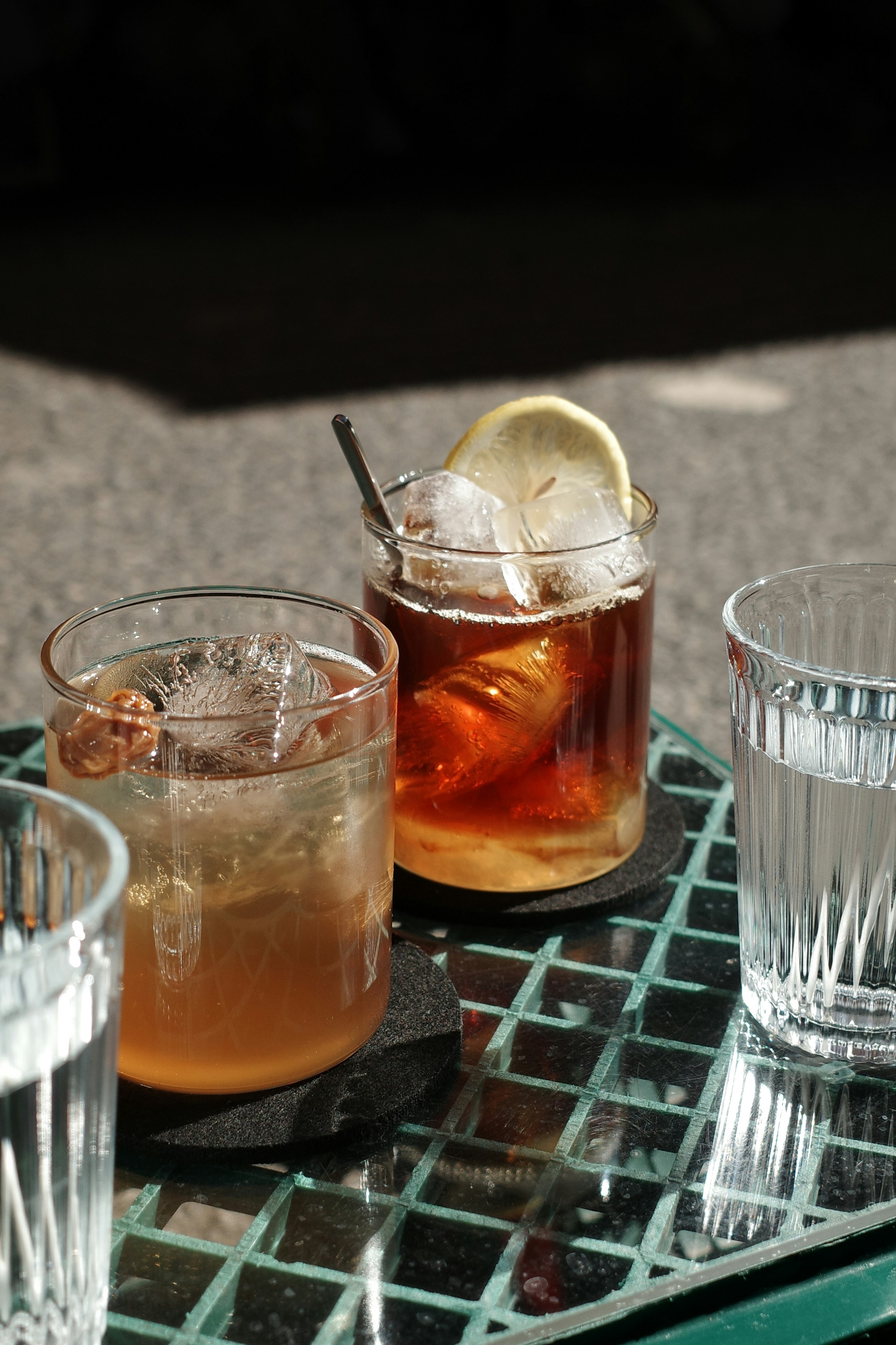 Two iced cocktails and water on a table