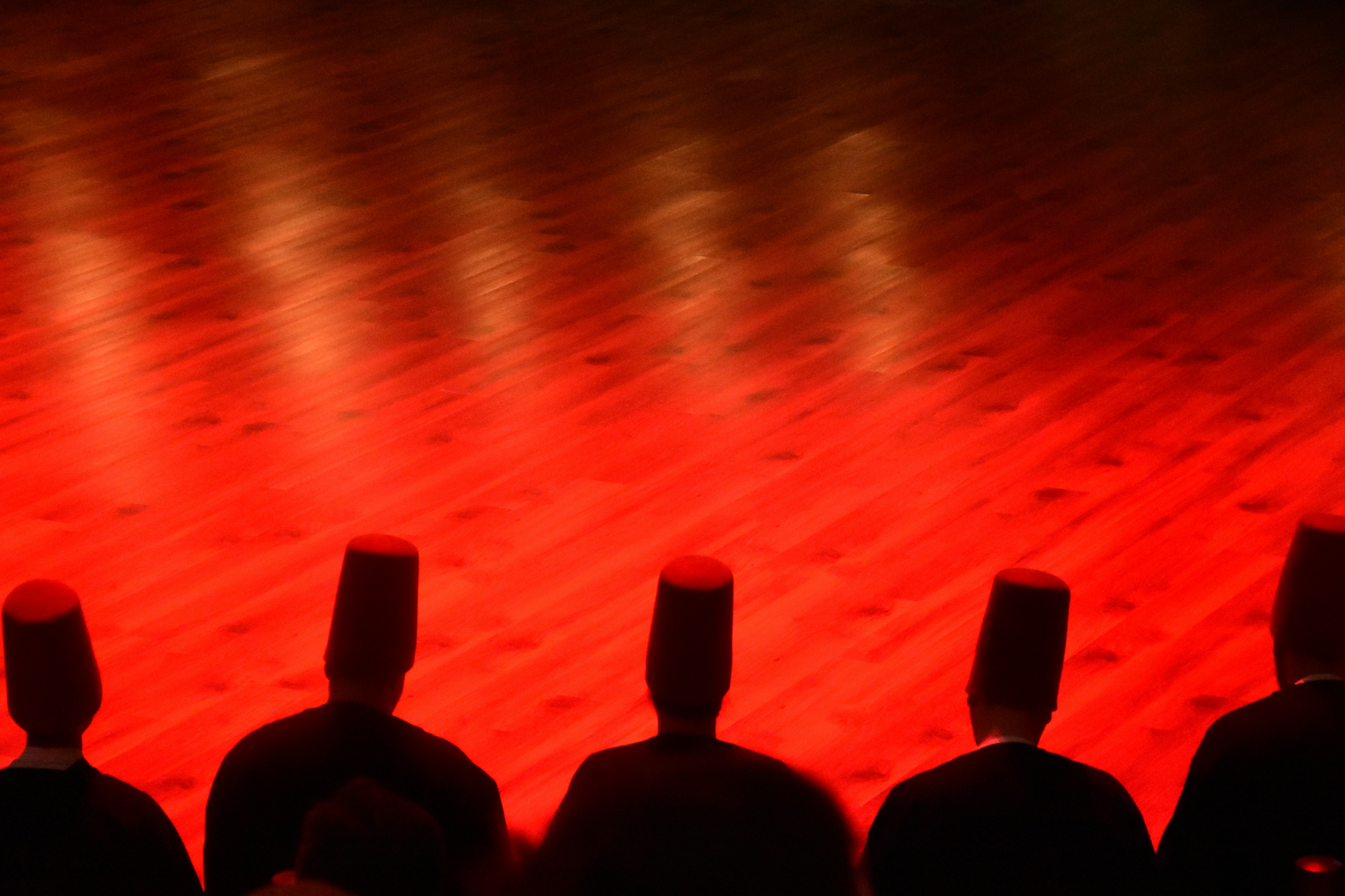 Five figures in dark robes and tall hats
