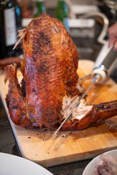 A golden-brown roasted turkey being carved on a wooden board