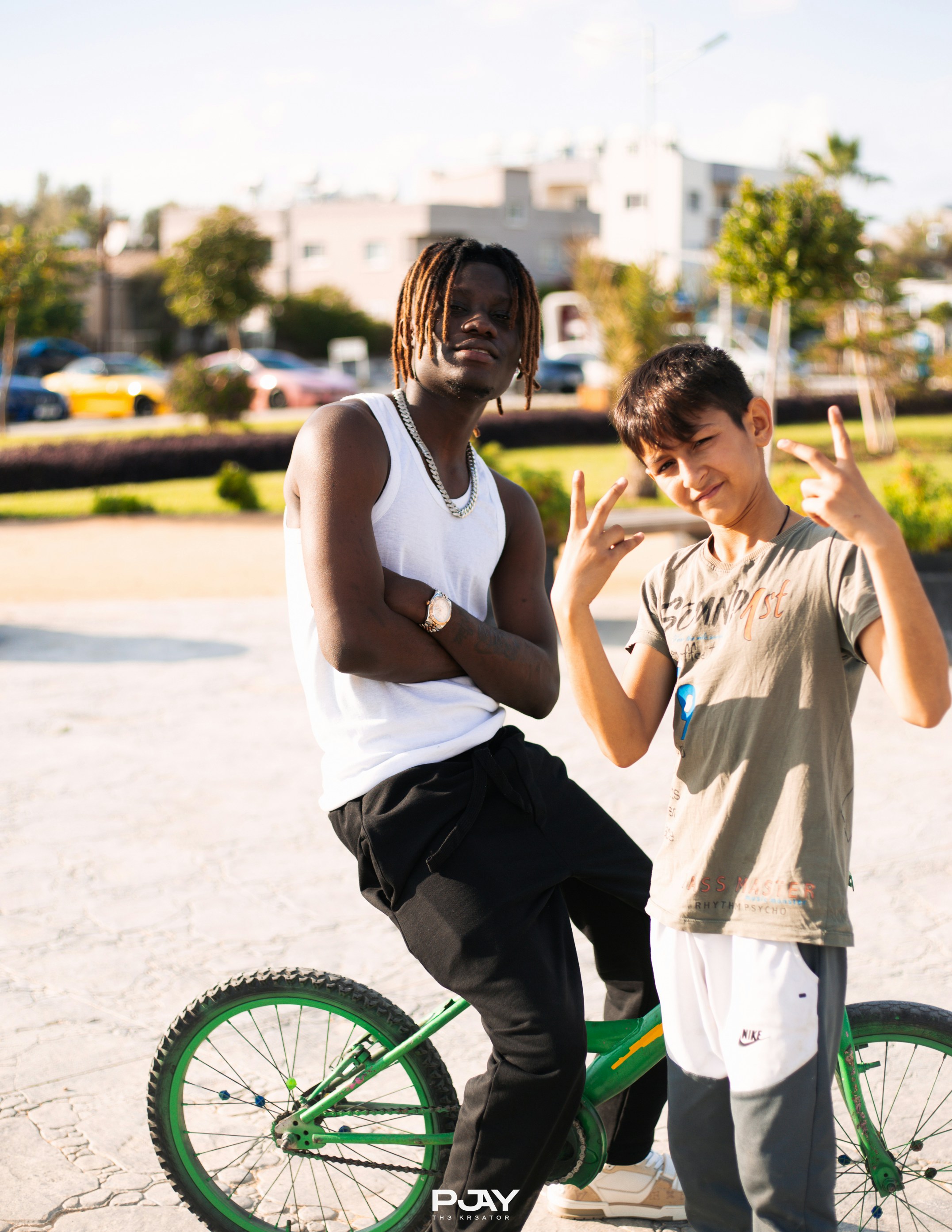 Zwei junge Männer, die draußen mit einem Fahrrad posieren.