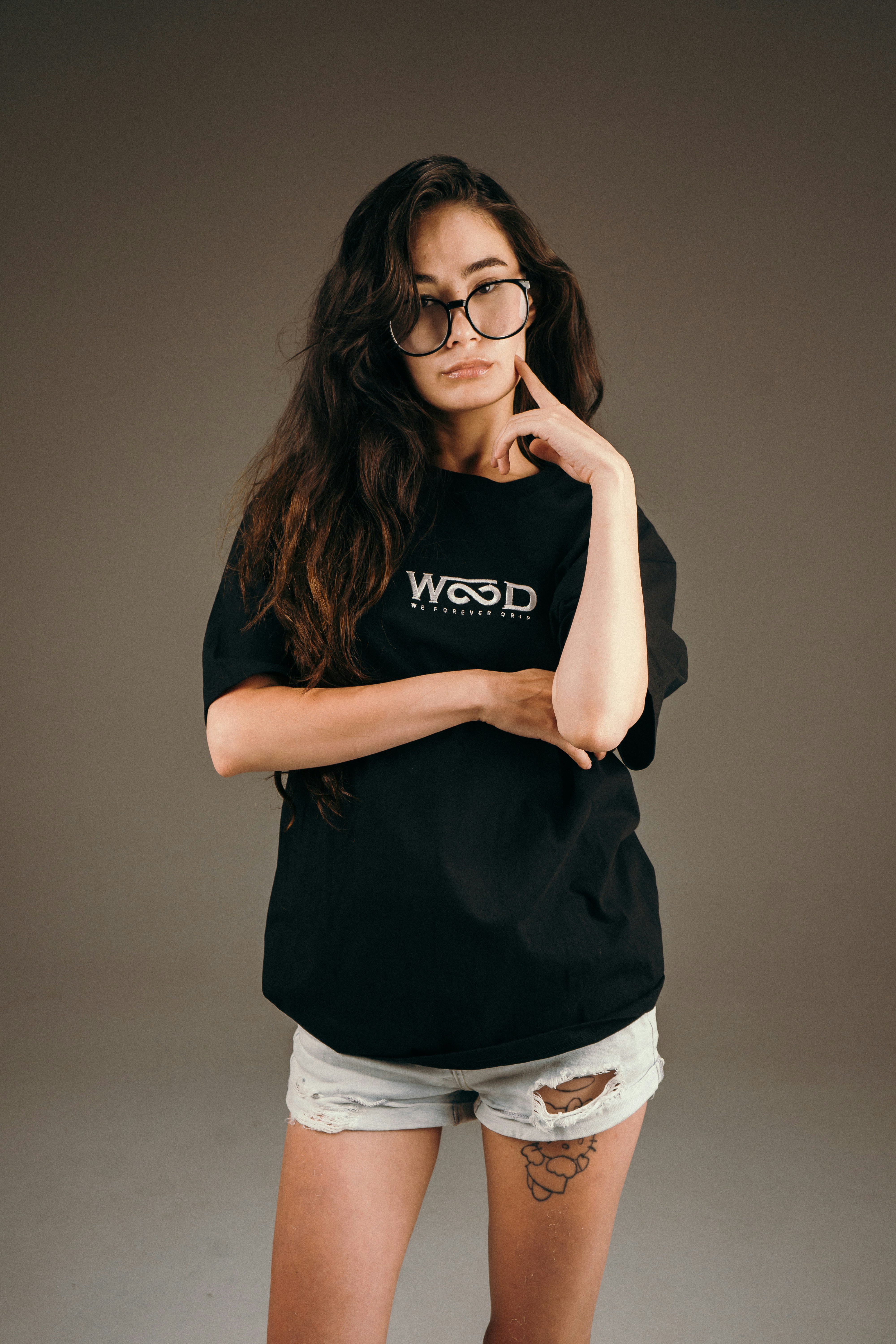 안경을 쓰고 검은 티셔츠를 입은 젊은 여성이 포즈를 취하고 있습니다.