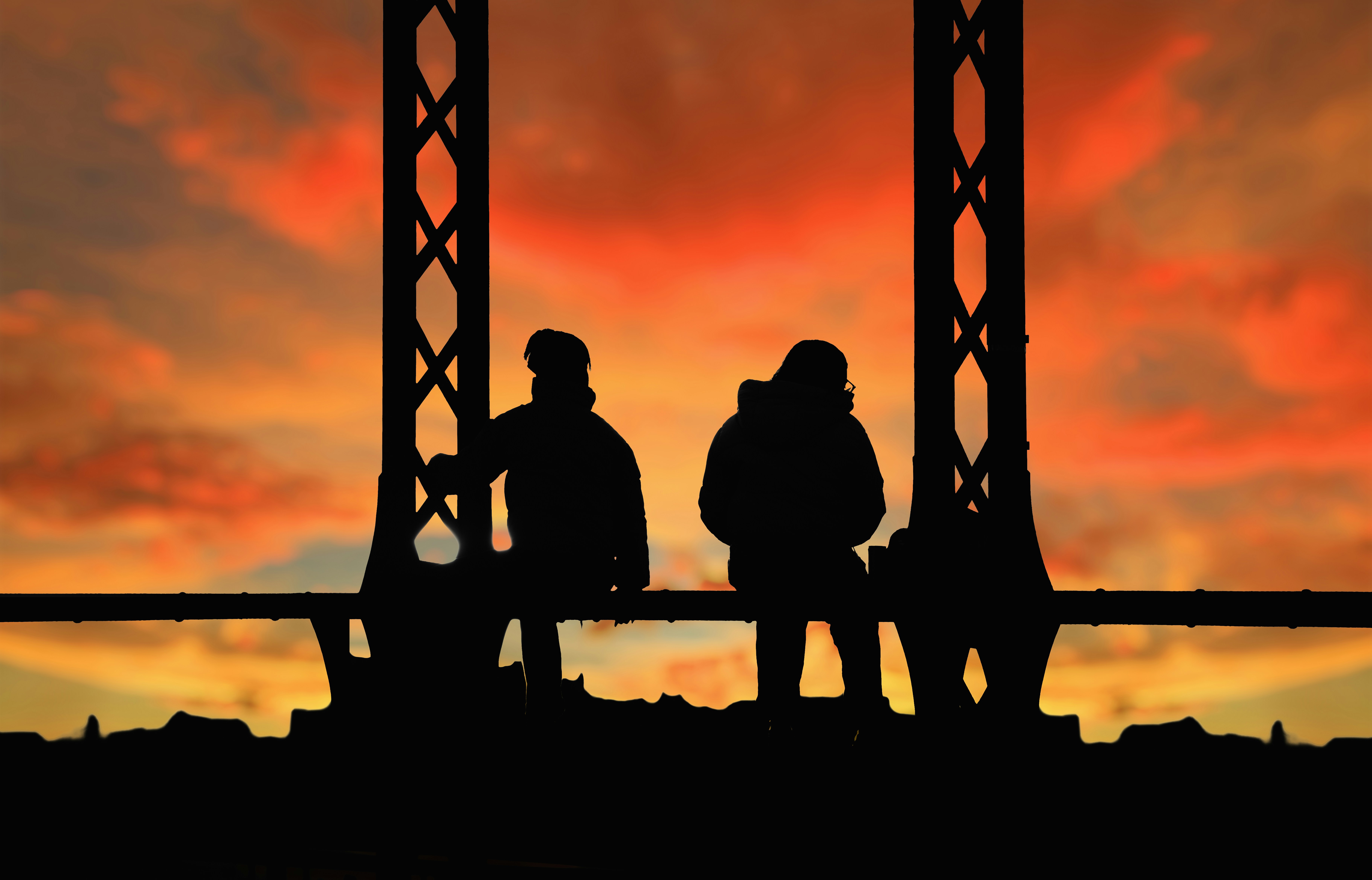 Two people silhouetted against a vibrant sunset sky.